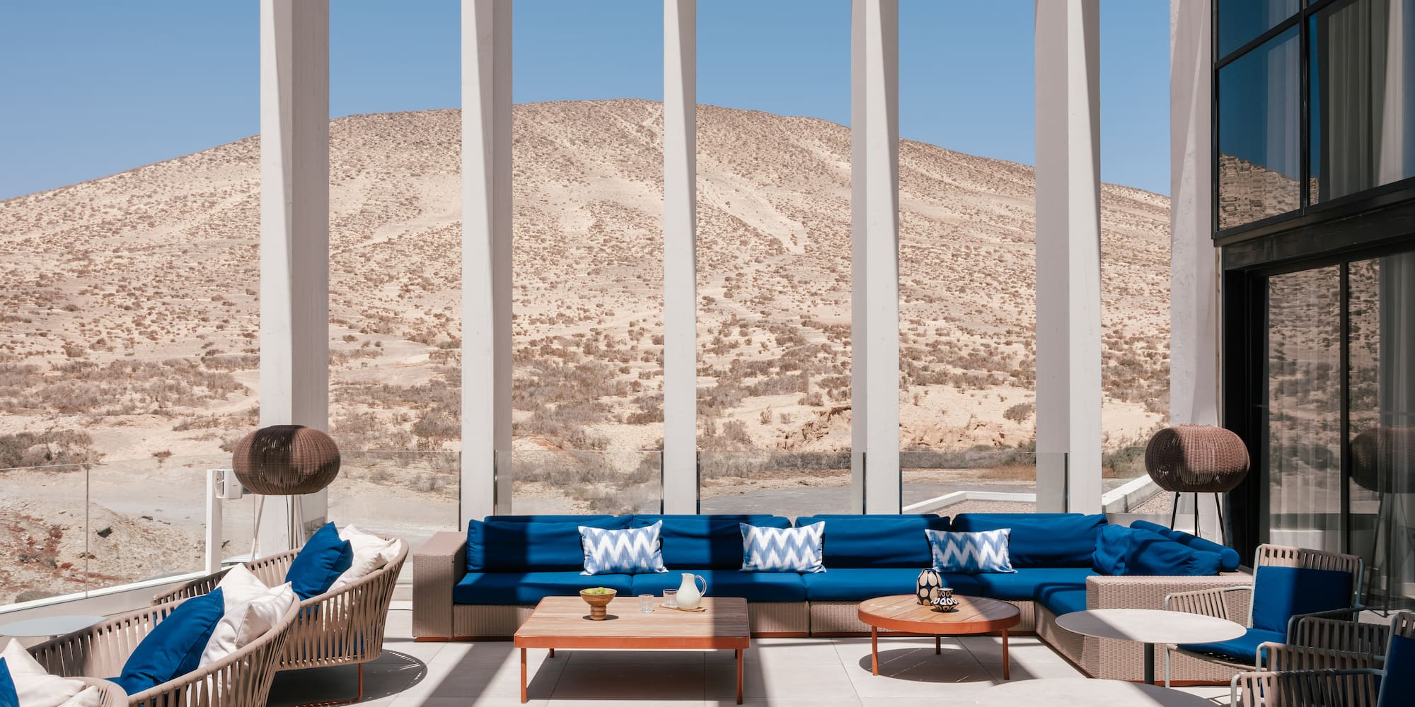 Modern outdoor lounge with blue seating and desert mountain view.
