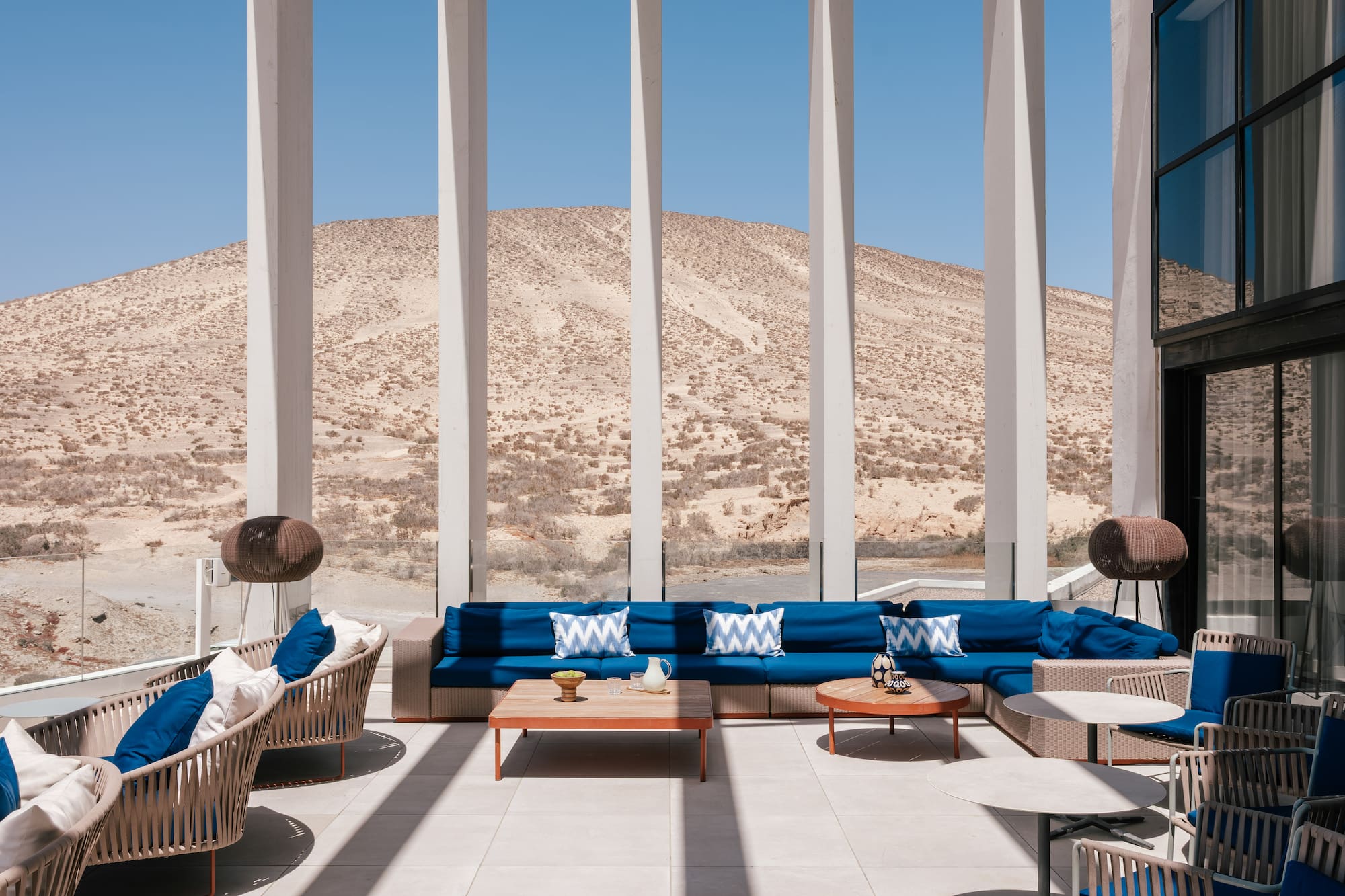 Modern outdoor lounge with blue seating and desert mountain view.