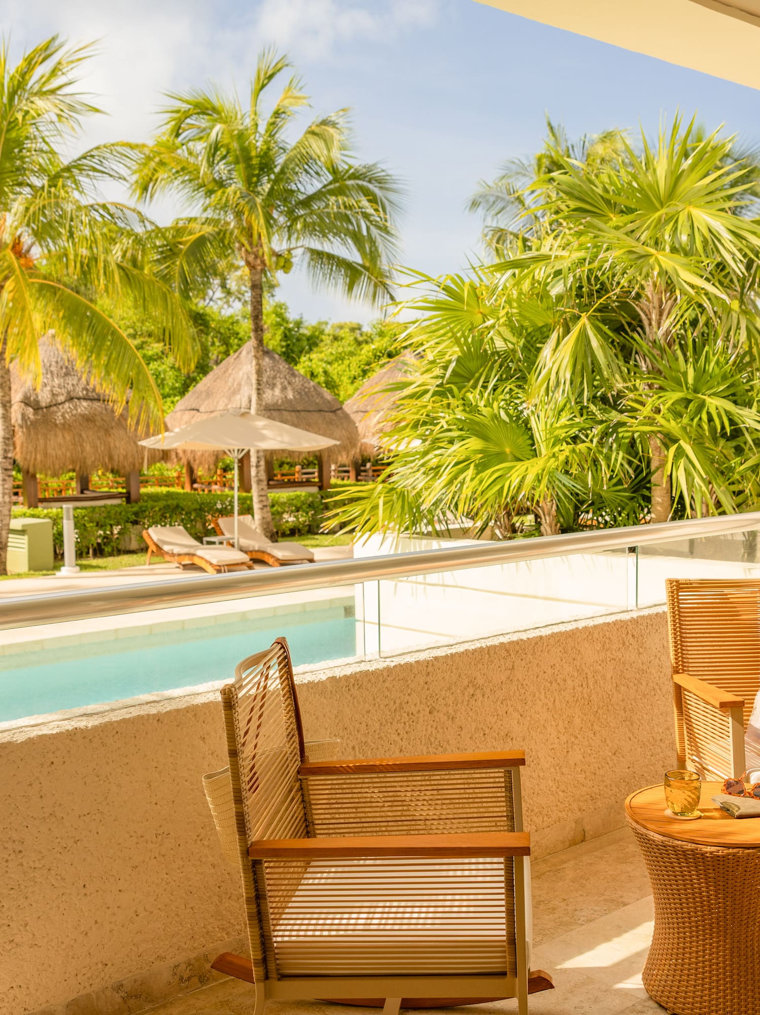 Hotel balcony with private jacuzzi, overlooking tropical pool and palm trees.