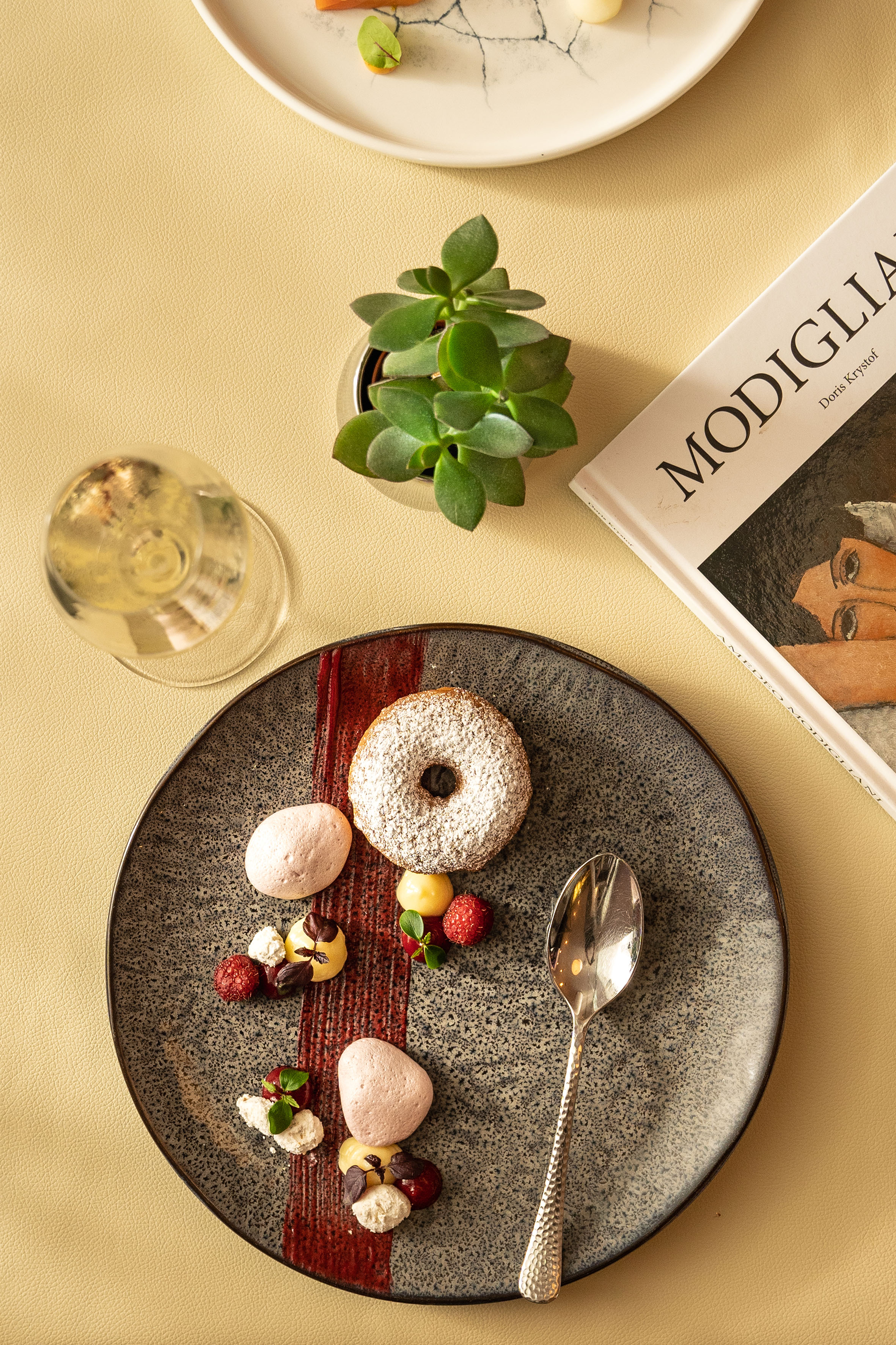 Fine dining powdered donut dessert, raspberries, meringues, wine, succulent.