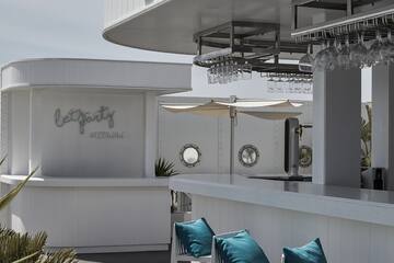 a white bar with blue pillows and glasses from the ceiling