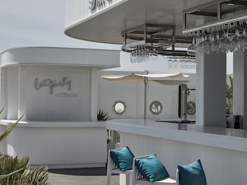 a white bar with blue pillows and glasses from the ceiling