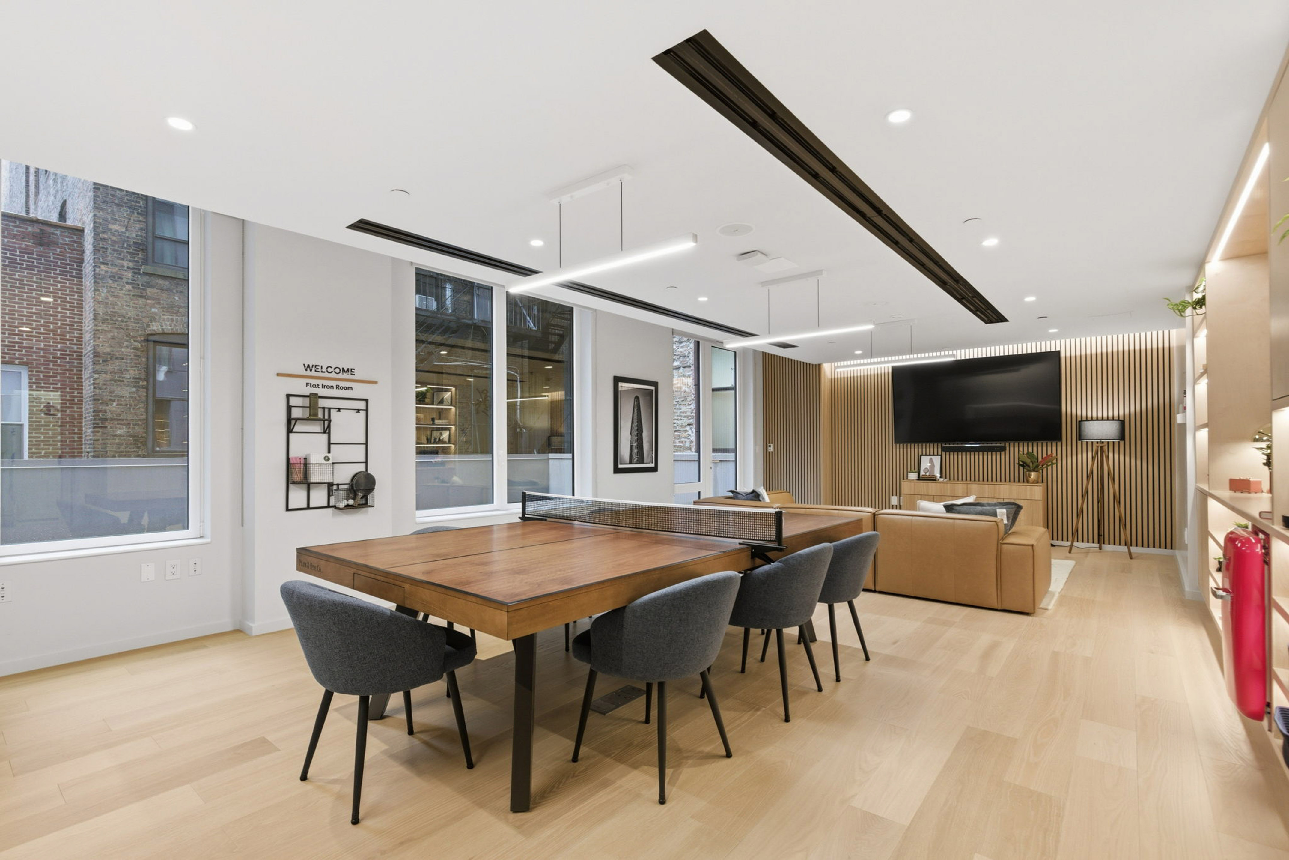 Modern Flat Iron Room lounge with ping pong table, sofa, TV, and wood floor.