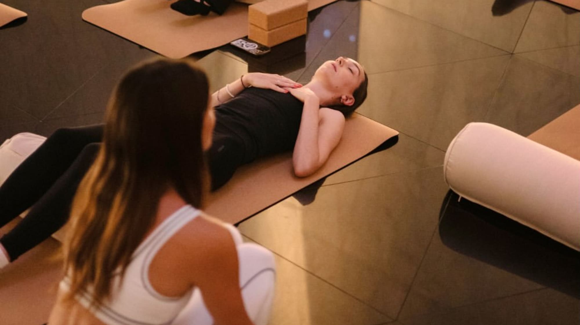 Women relaxing on yoga mats with bolsters and blocks, practicing restorative yoga.