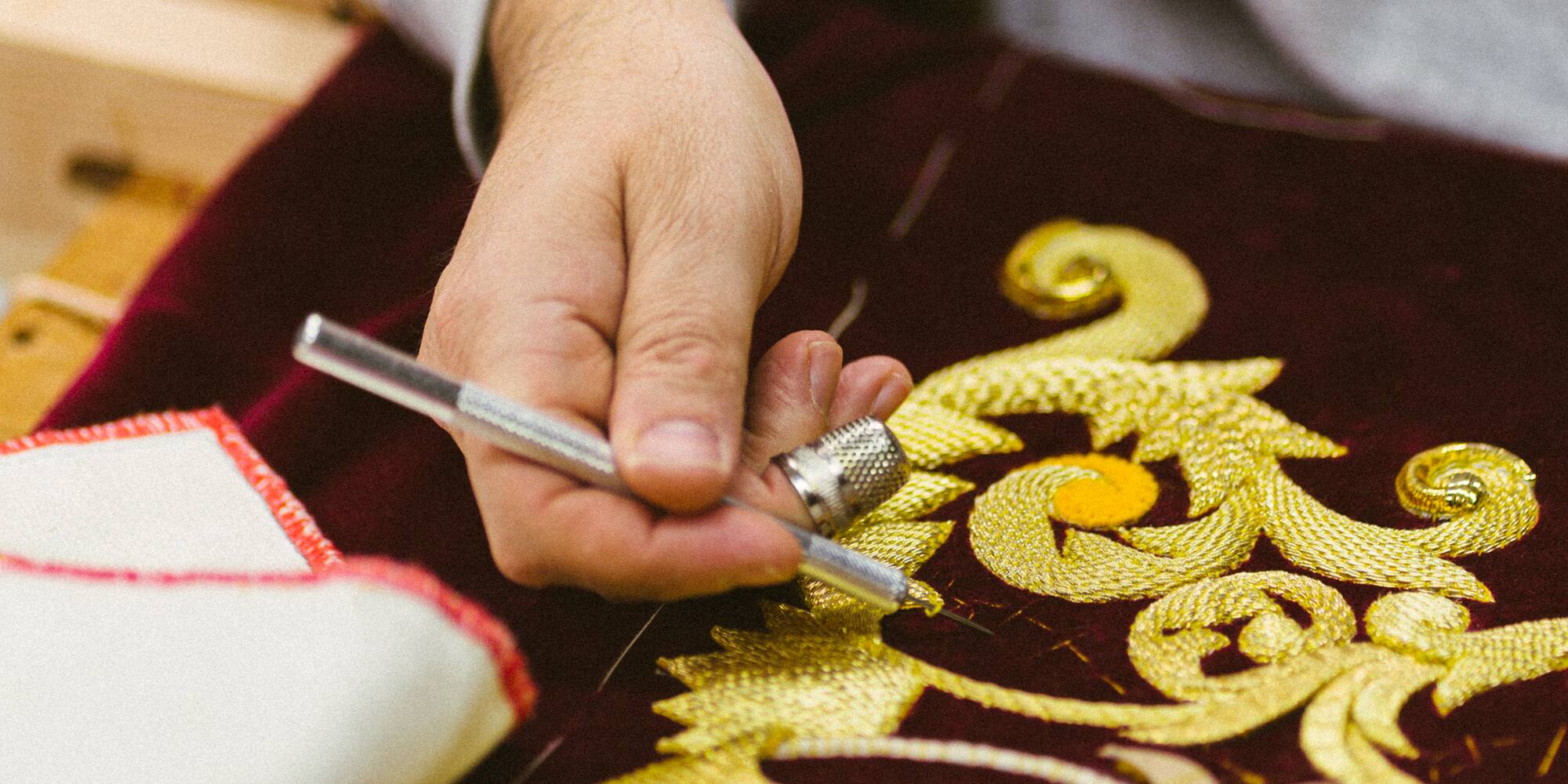 a person drawing a design on a red cloth