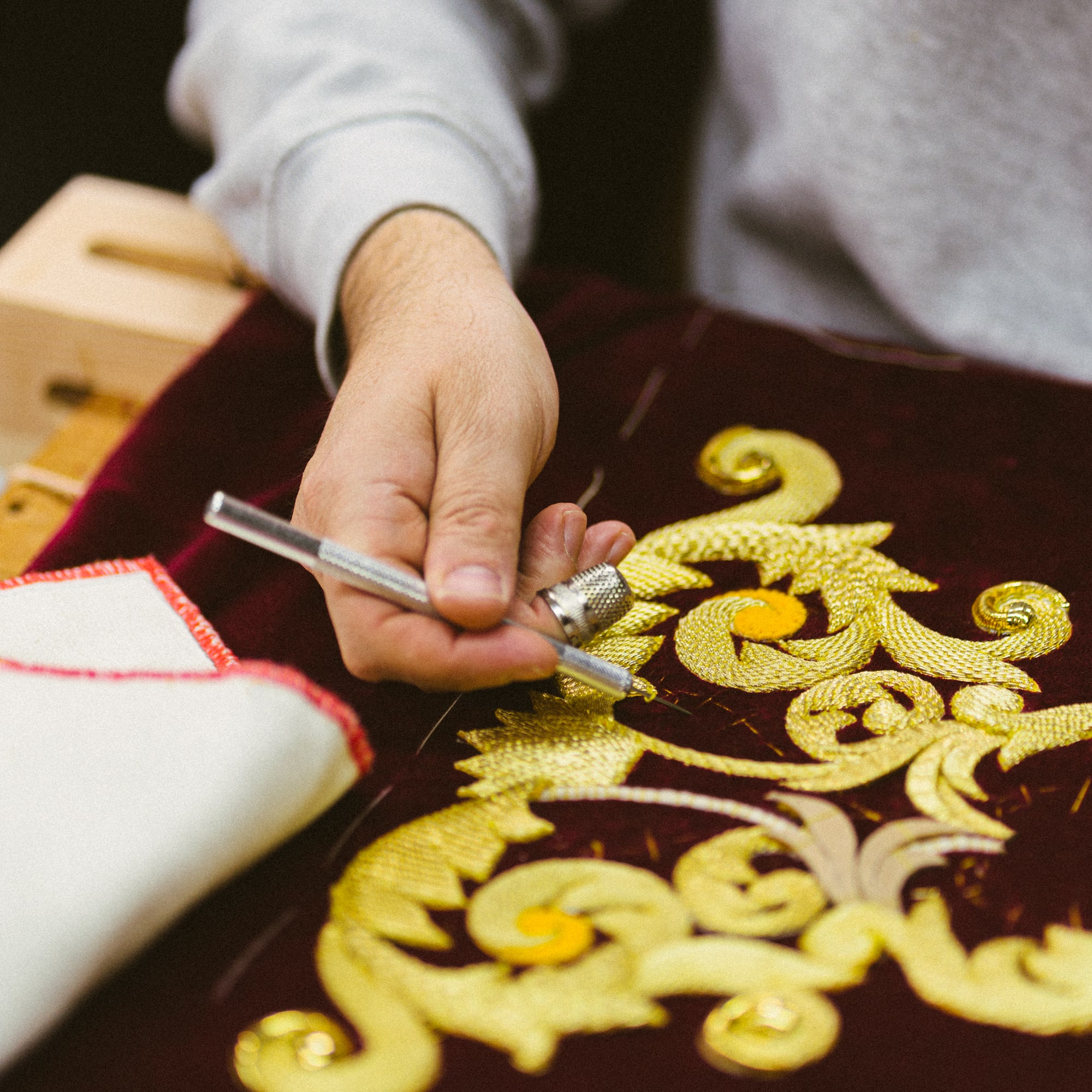 a person drawing a design on a red cloth