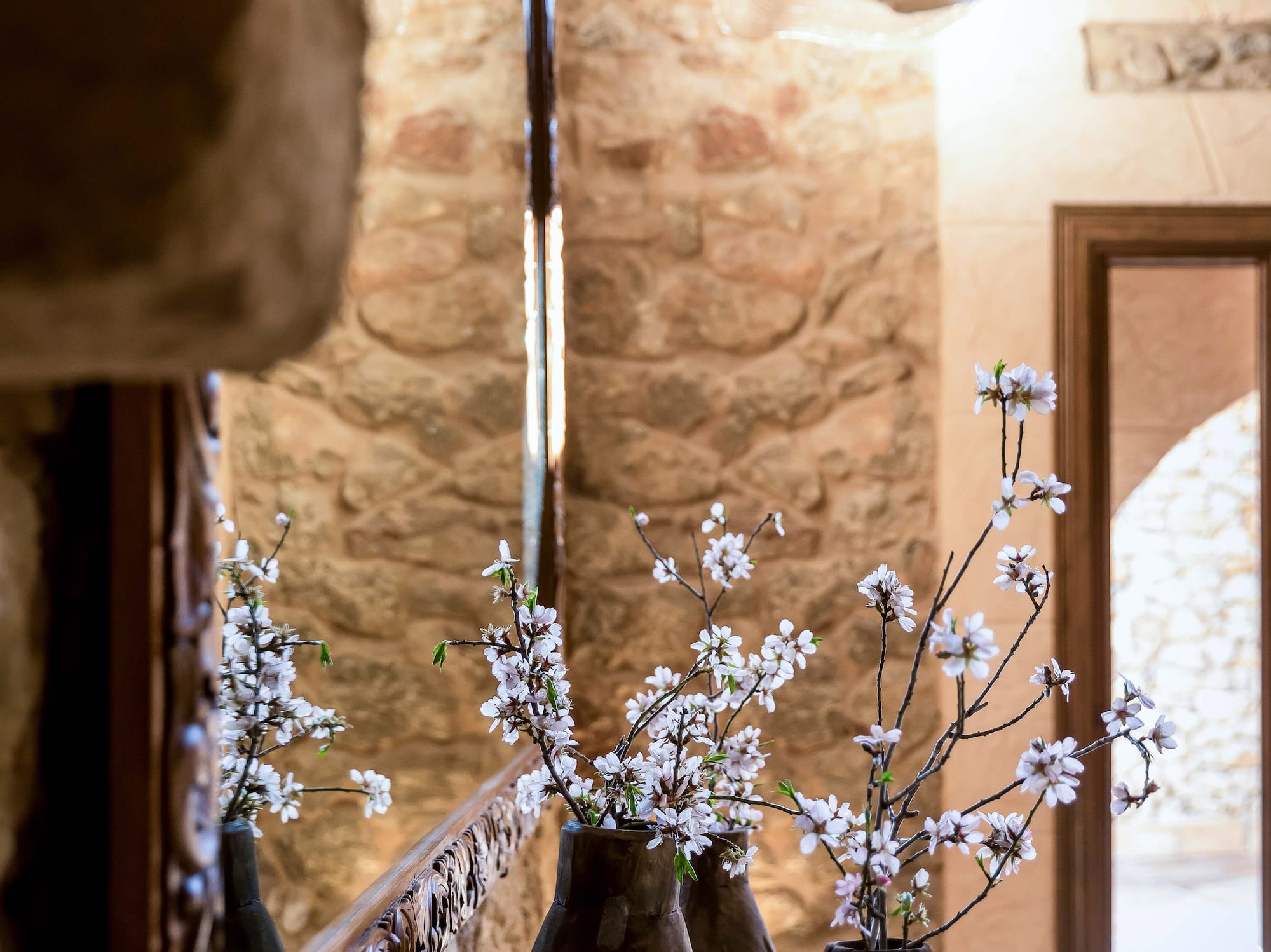 a vases with white flowers in front of a mirror
