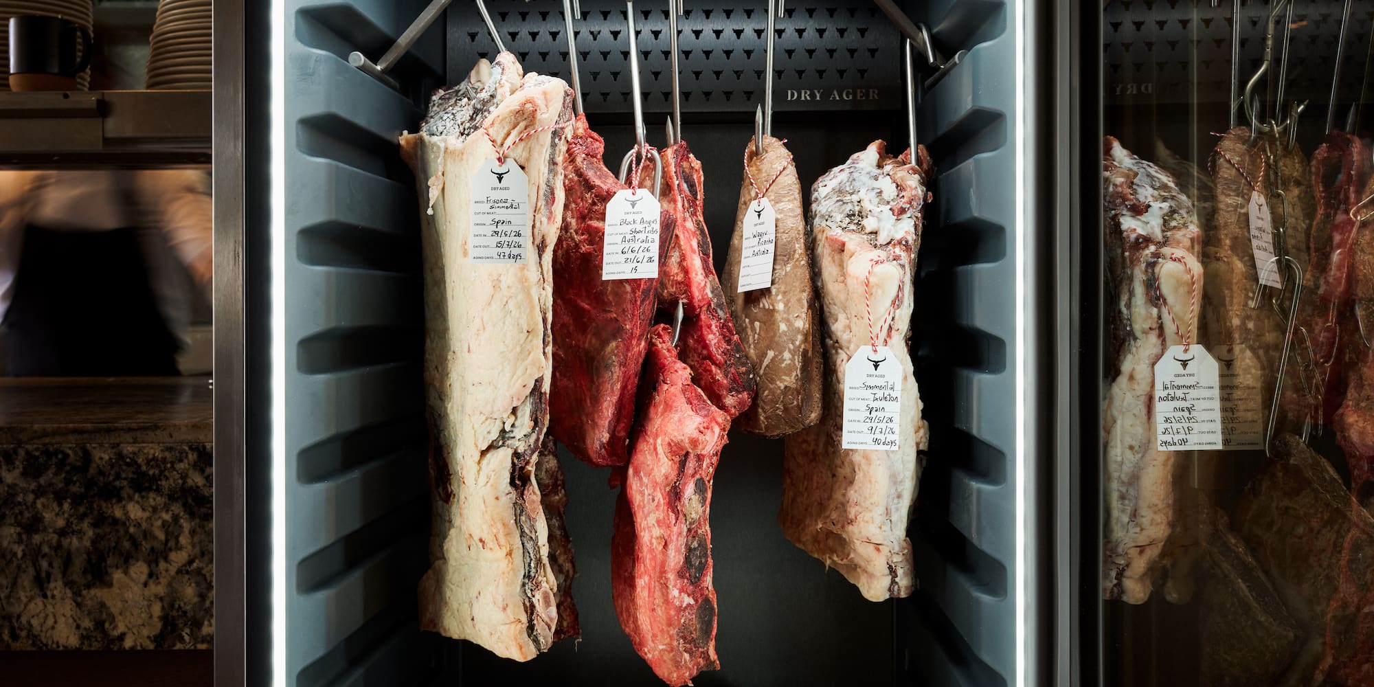 Dry-aged beef cuts: Simmental & Black Angus, in a lighted Dry Ager.