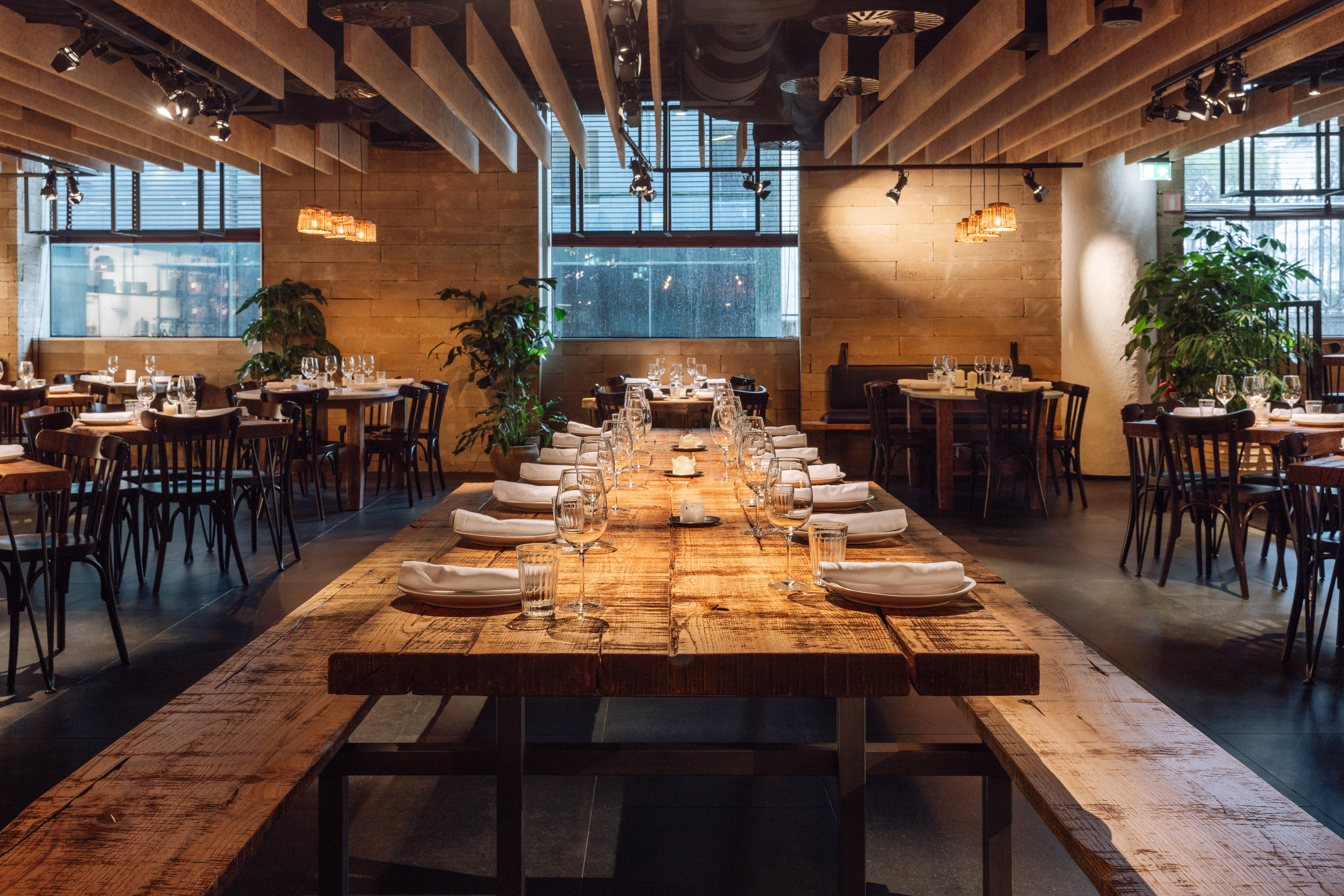 Rustic modern restaurant dining room with a long communal wooden table.