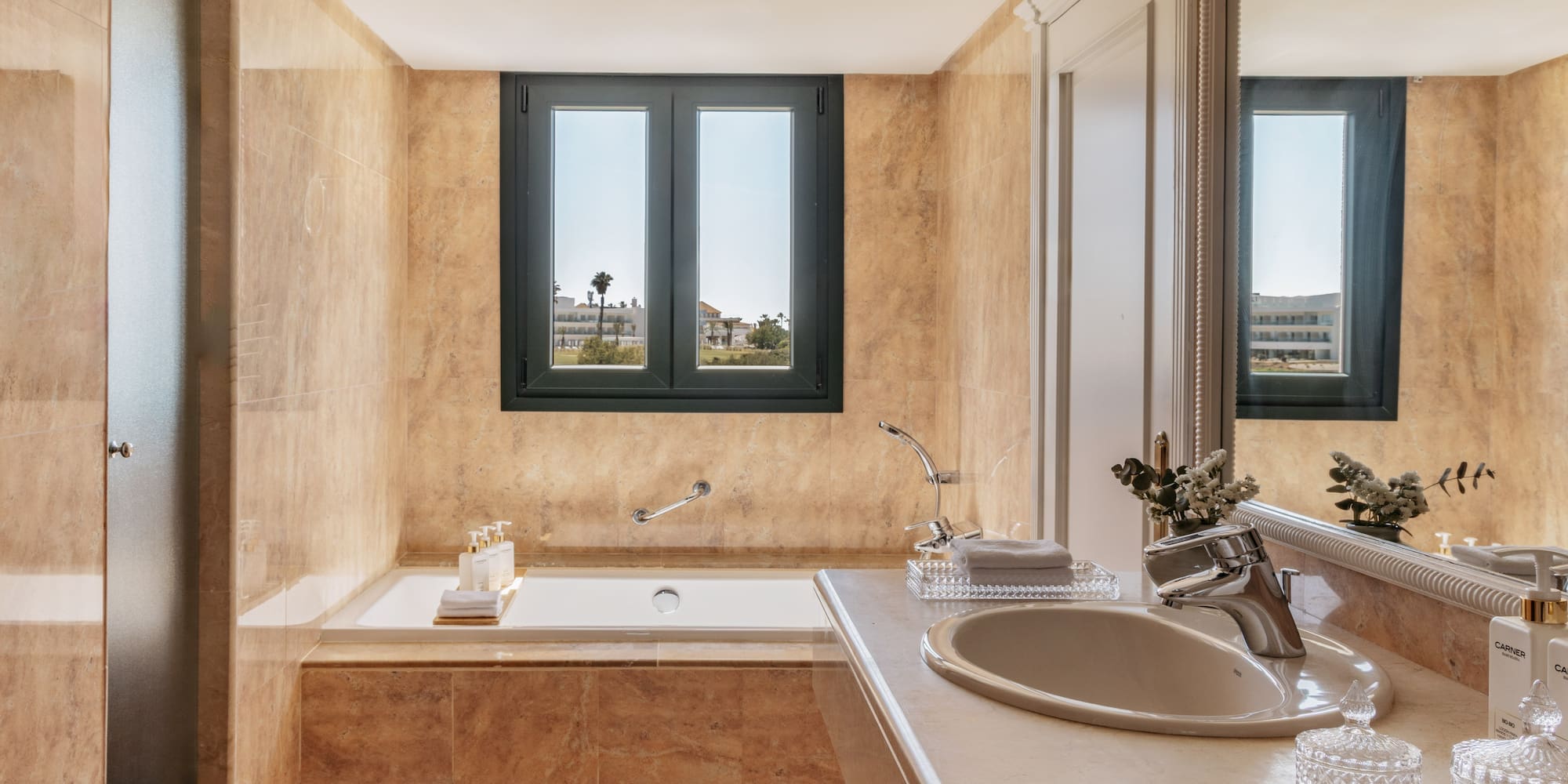 Elegant beige marble bathroom with built-in tub and outdoor window view.