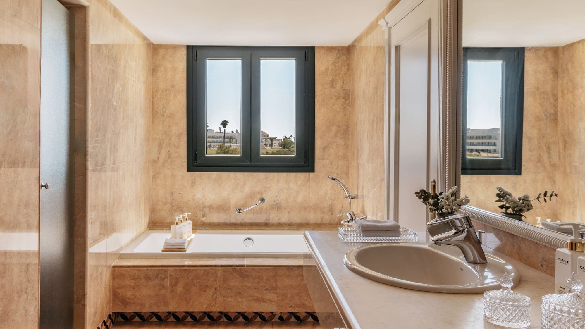 Elegant beige marble bathroom with built-in tub and outdoor window view.