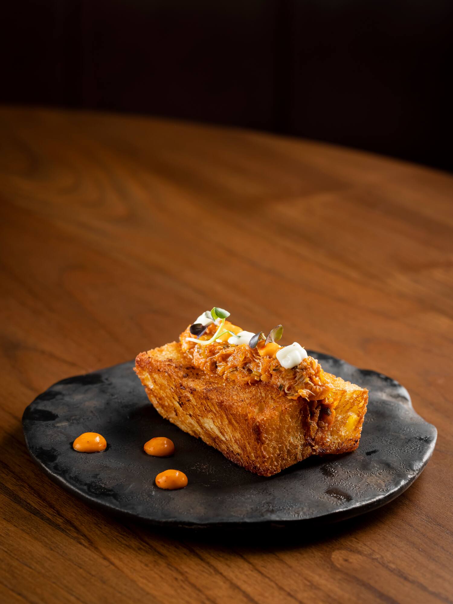 a piece of bread with toppings on a black plate