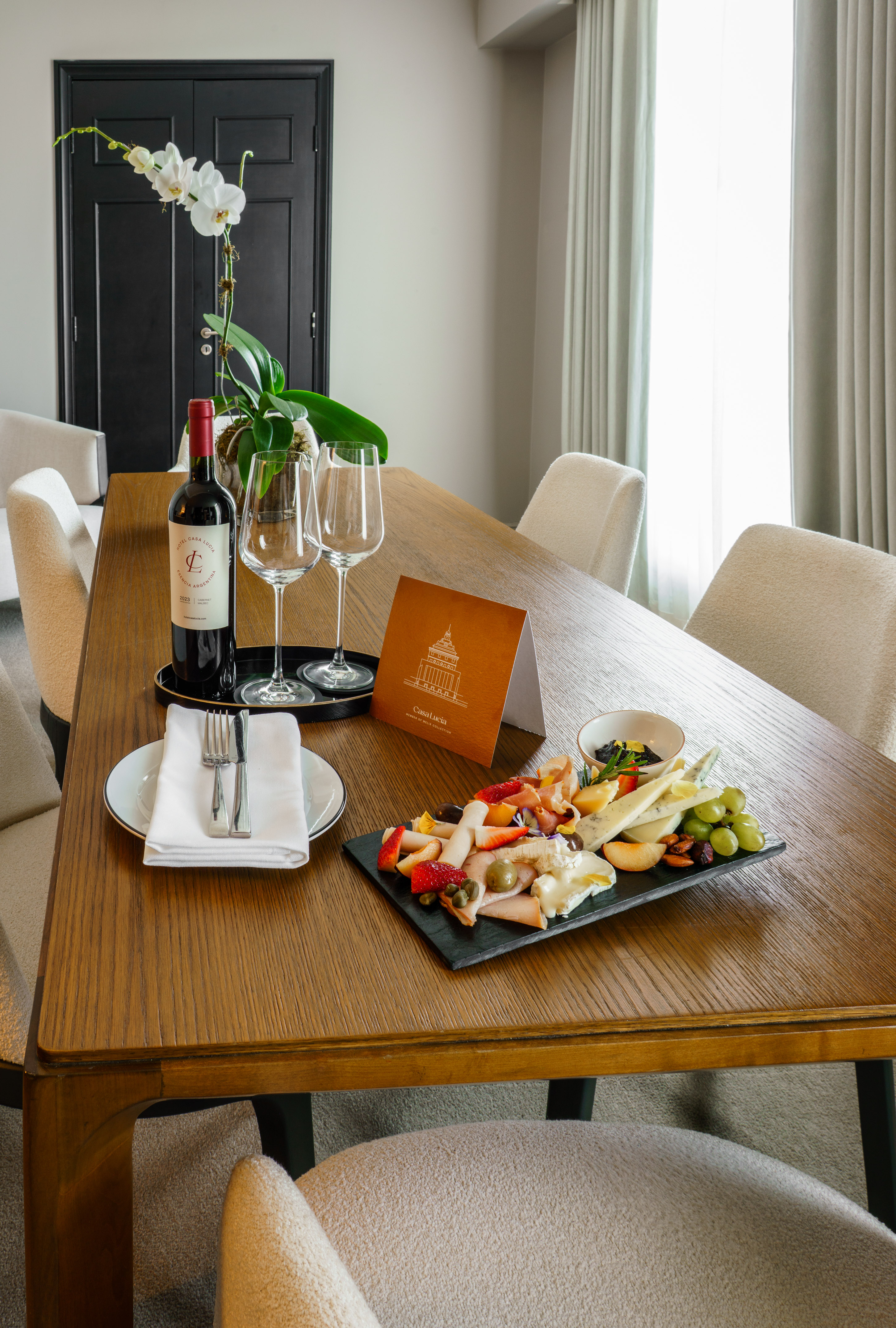 Hotel charcuterie board with red wine, assorted cheeses, fruits, and meats.