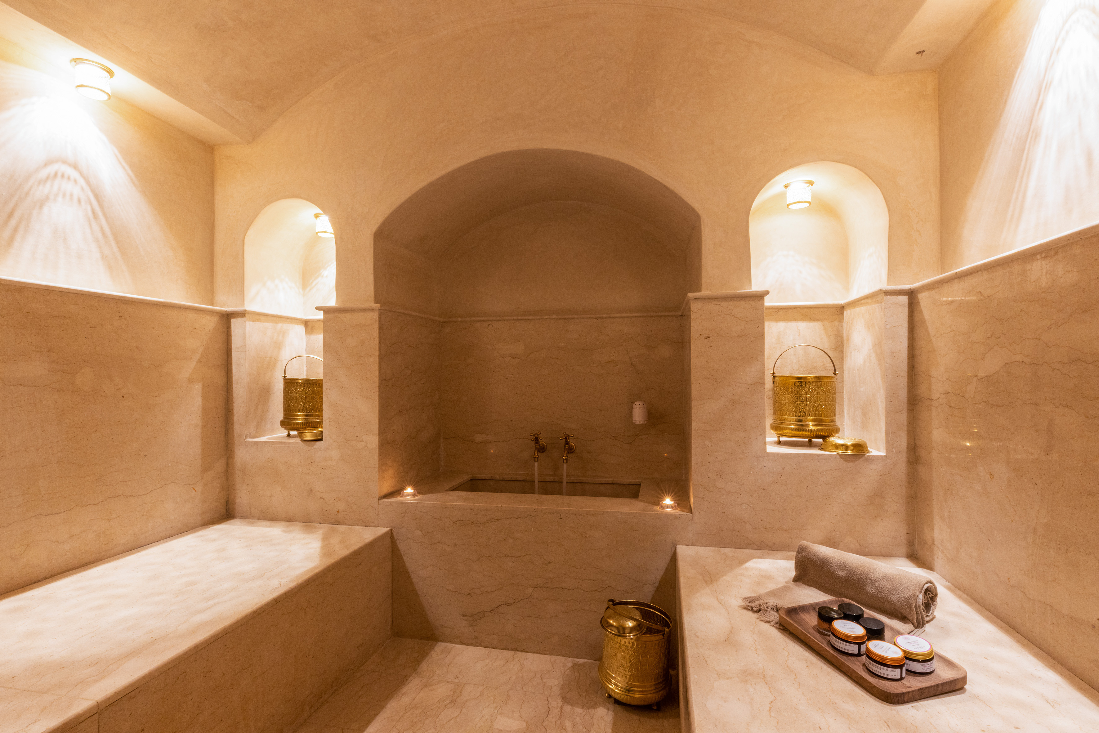 Luxury marble Hammam spa with golden accents, bathing area, and relaxation benches.