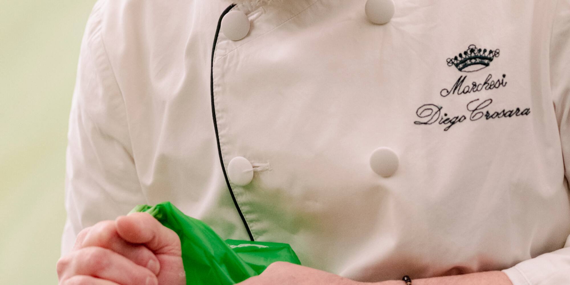 a man in a chef's uniform decorating a cake
