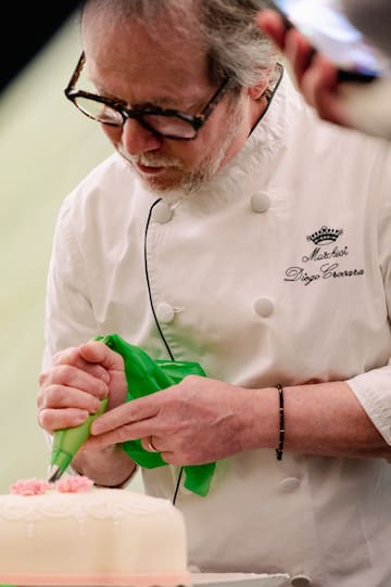 a man in a chef's uniform decorating a cake