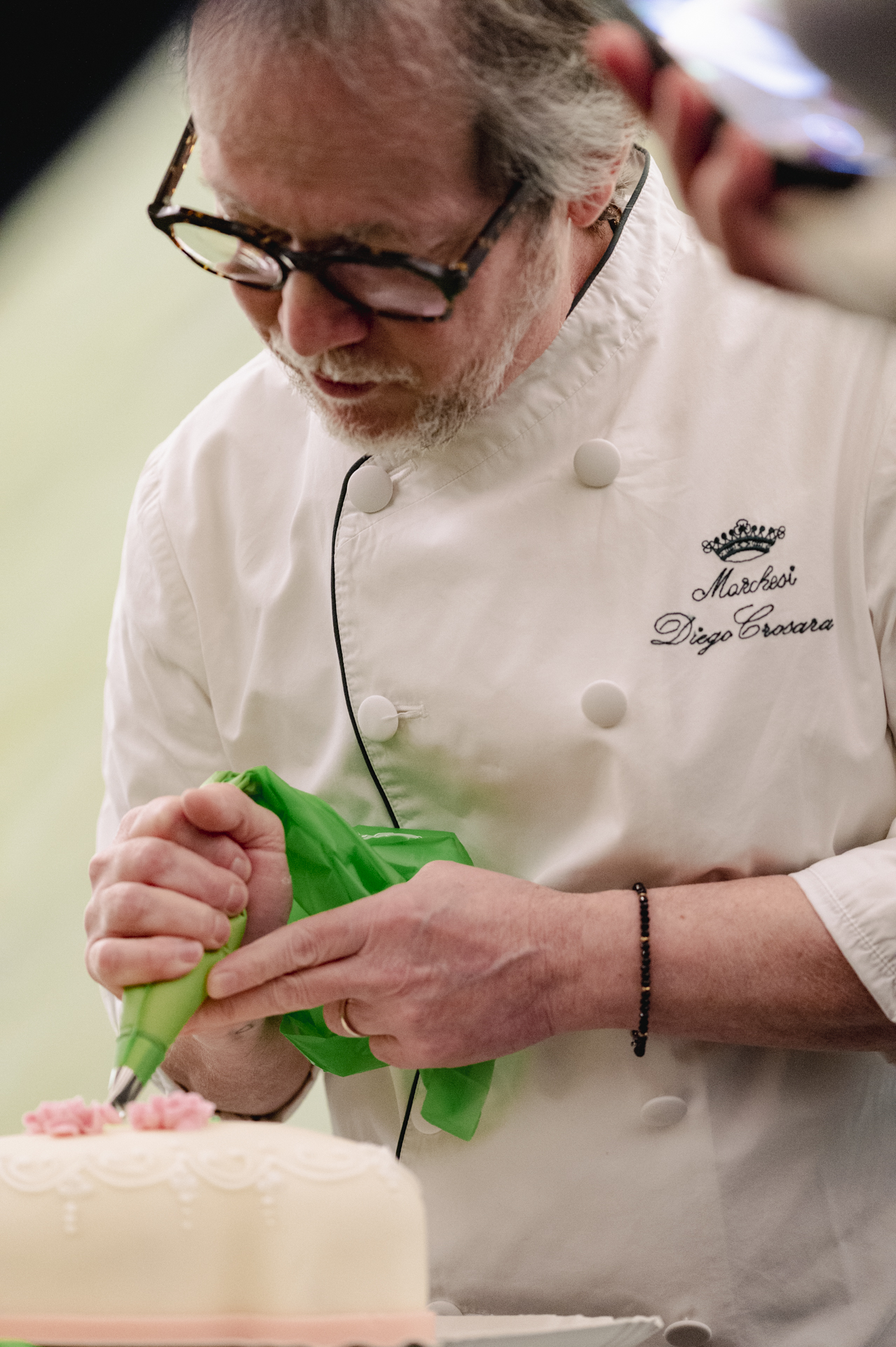 a man in a chef's uniform decorating a cake