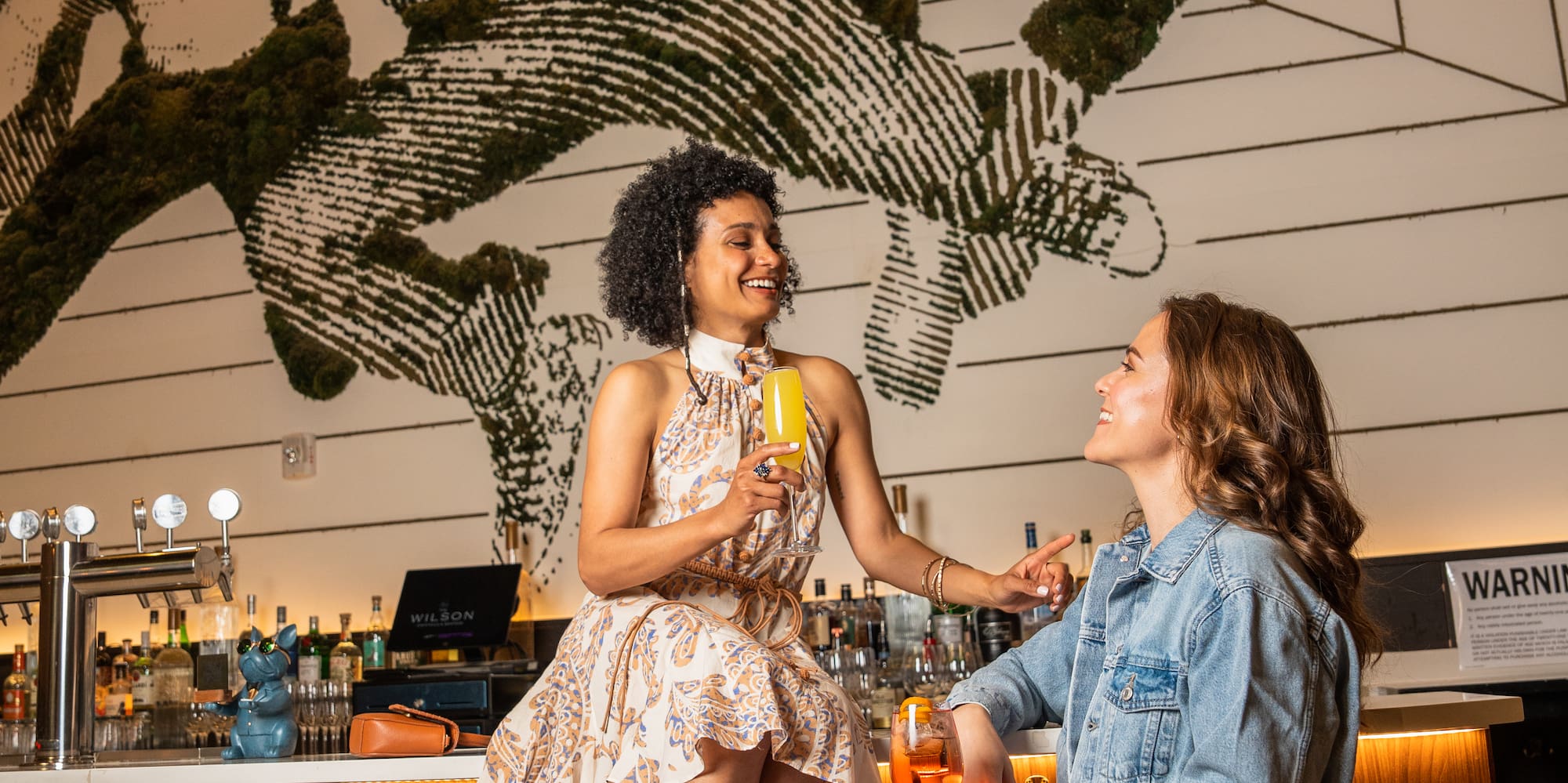 two women sitting on stools in a bar
