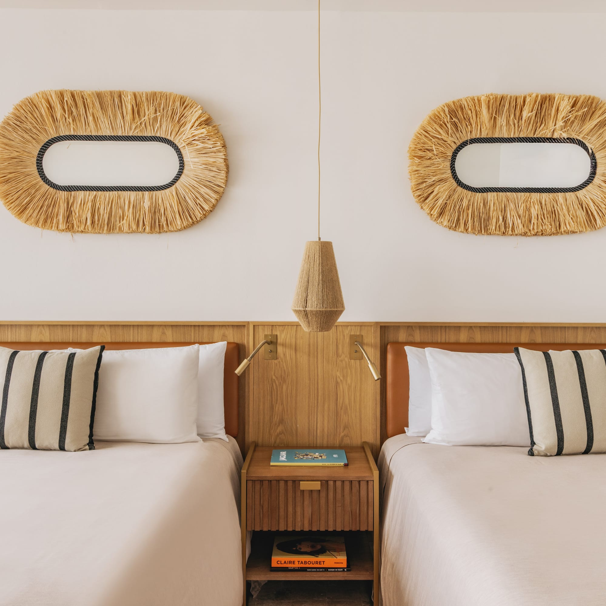 Boho twin room with wooden headboards, raffia mirrors, and striped pillows.