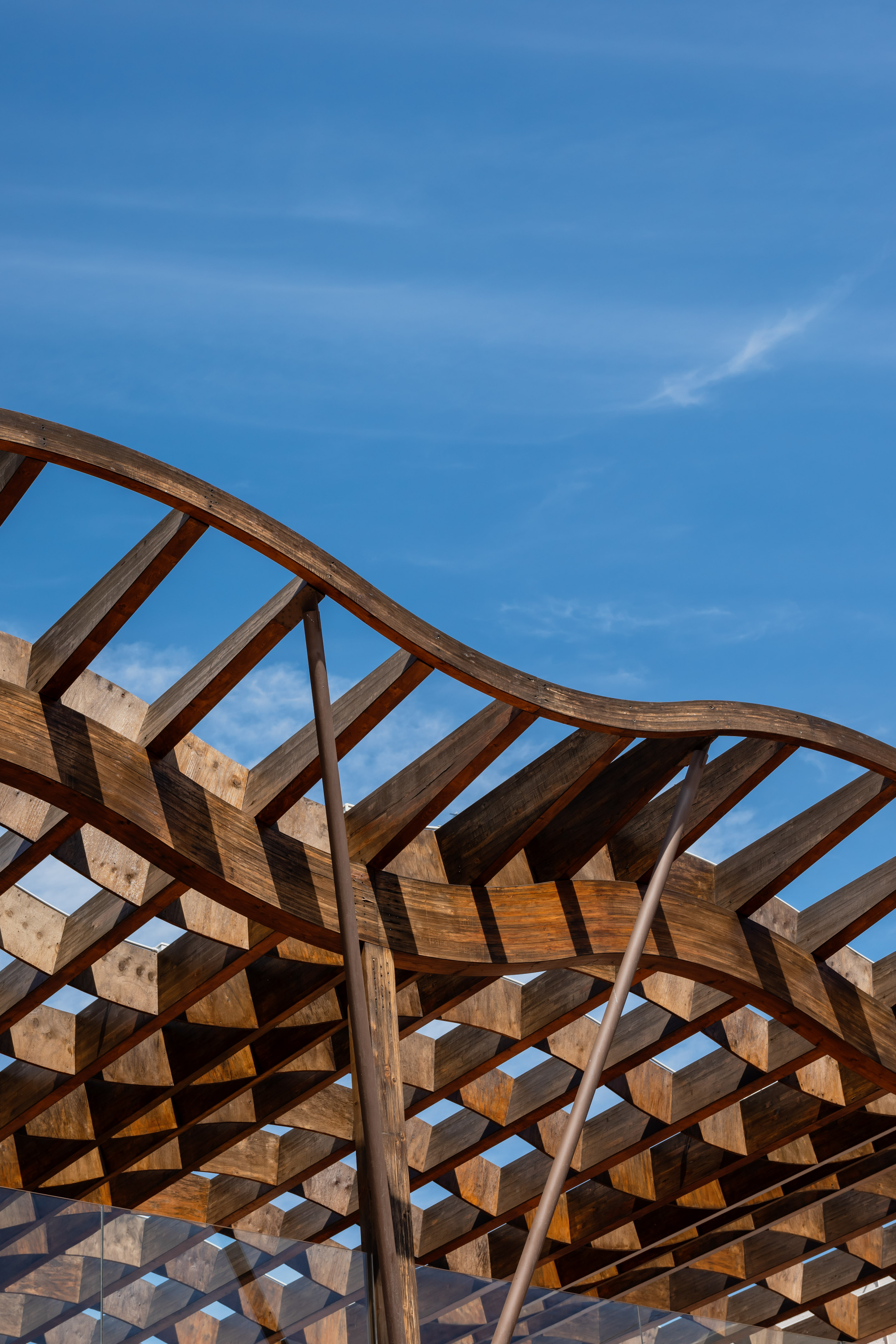 Geometric wooden pergola design under clear blue sky.