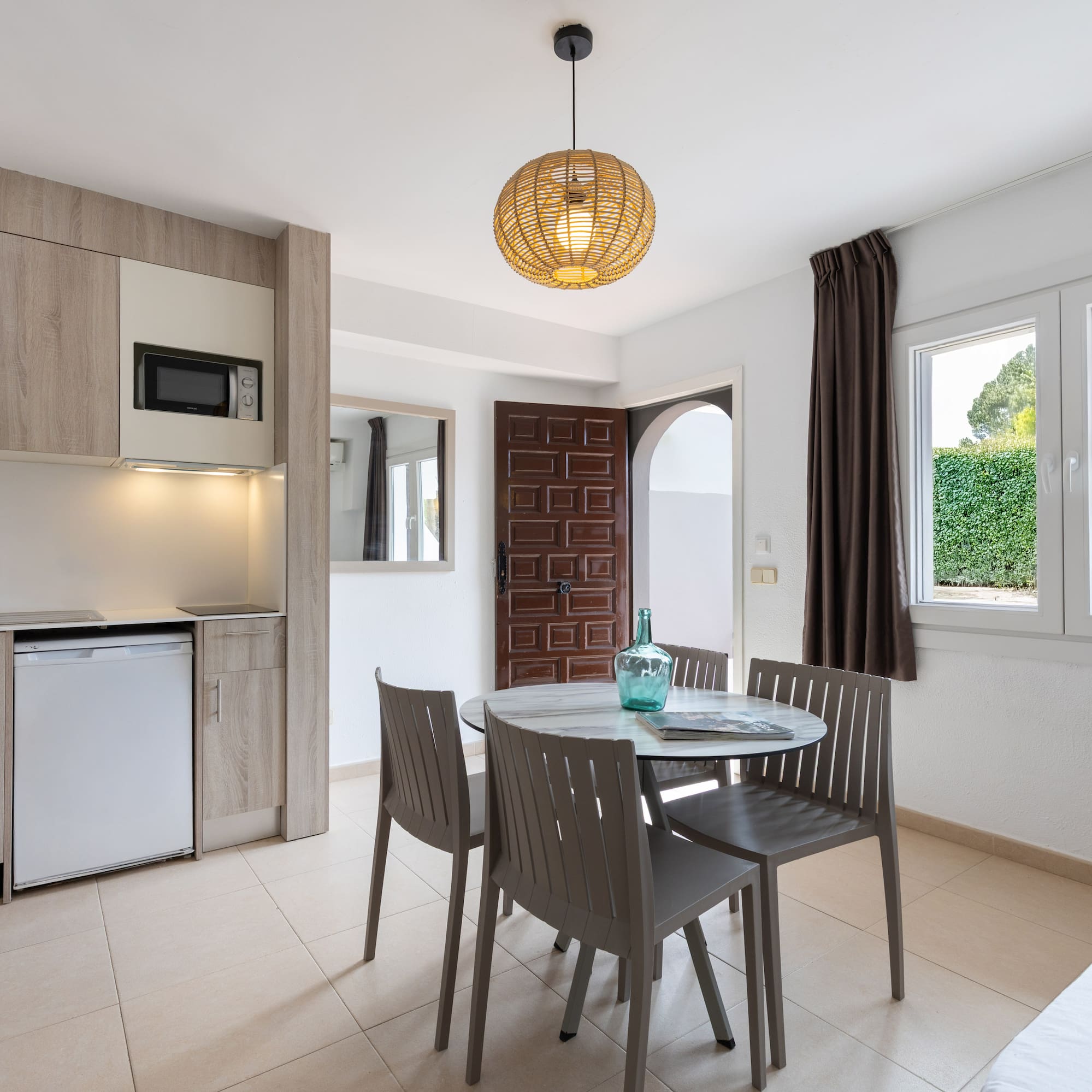 Modern studio apartment with kitchenette, dining table, and window.
