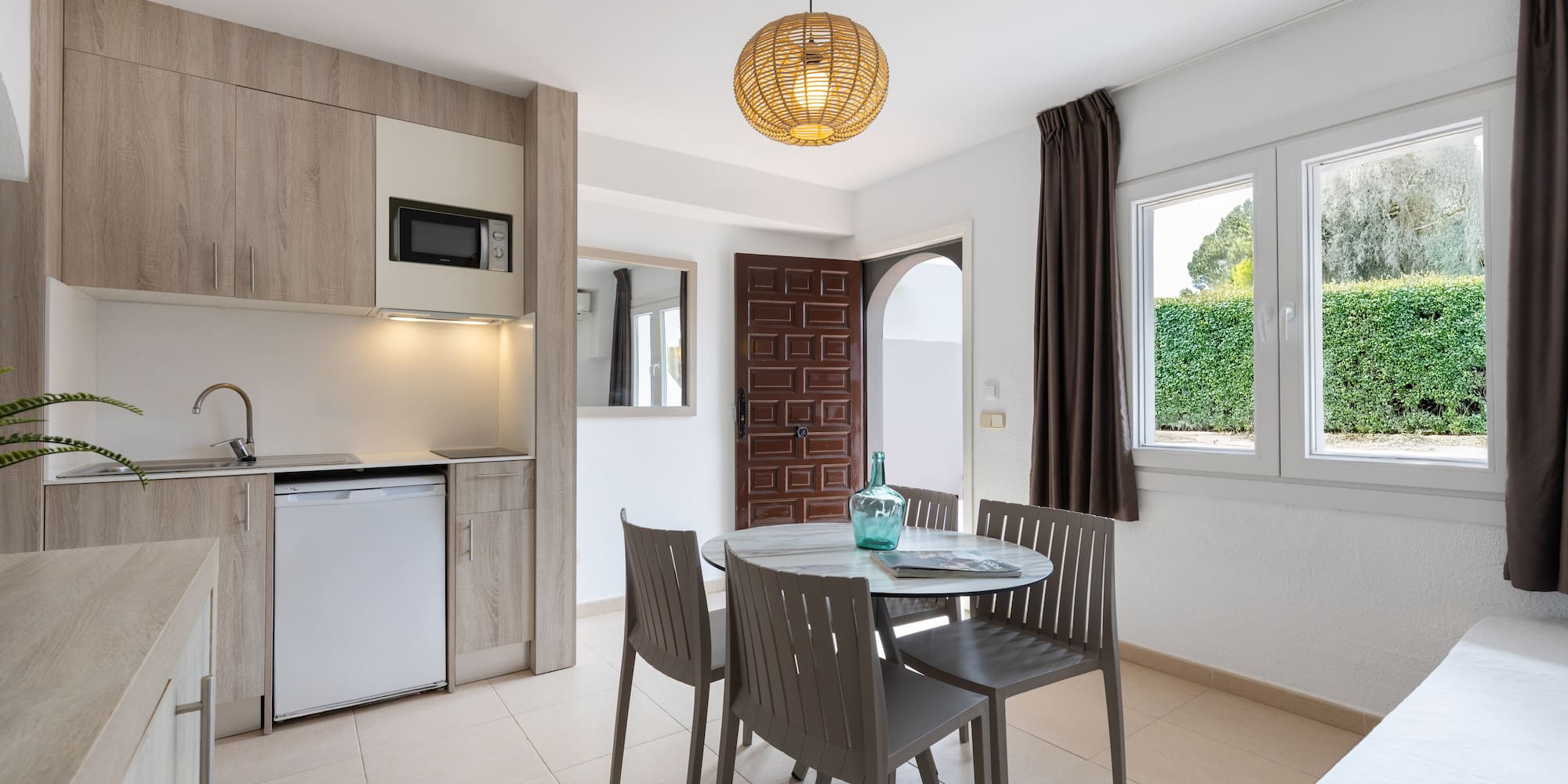 Modern studio apartment with kitchenette, dining table, and window.