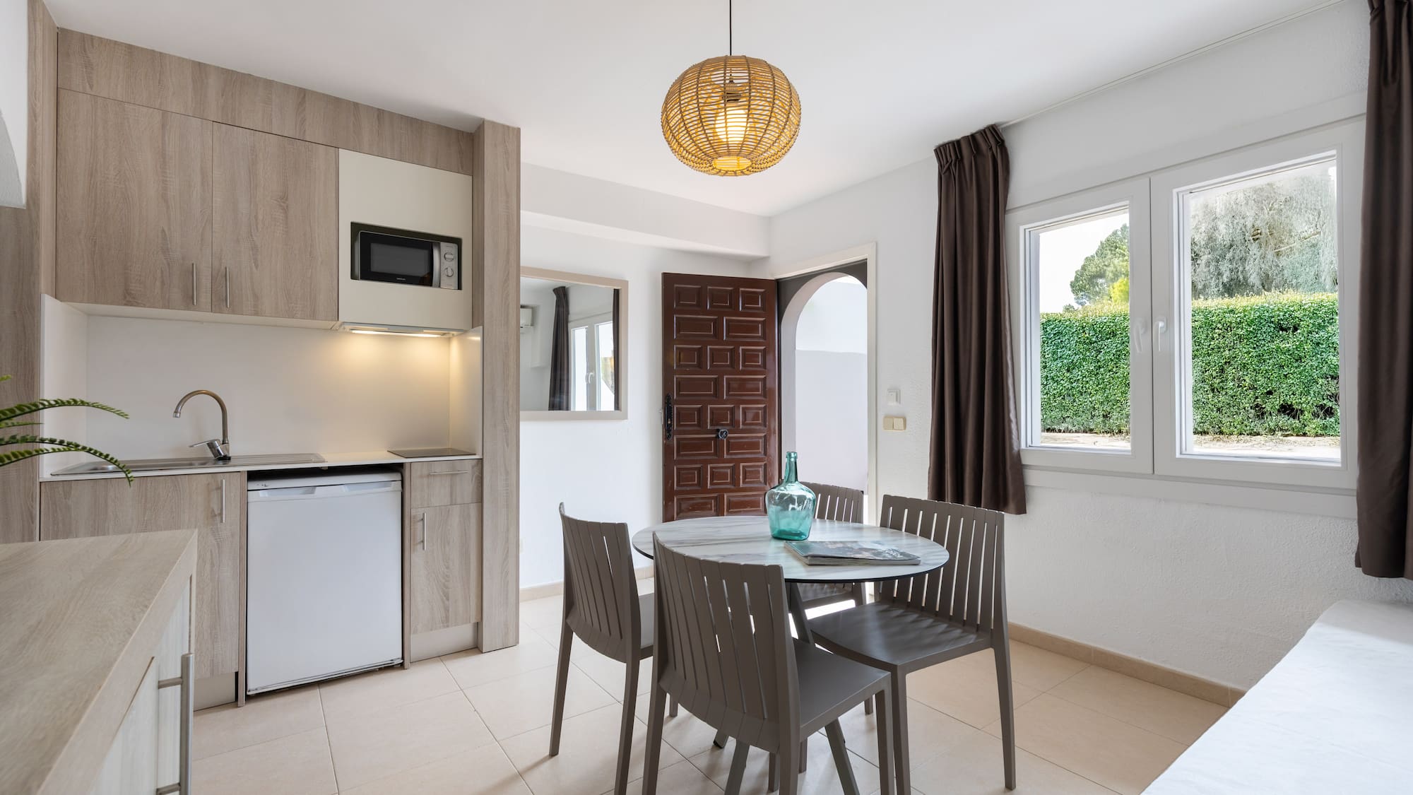 Modern studio apartment with kitchenette, dining table, and garden view.