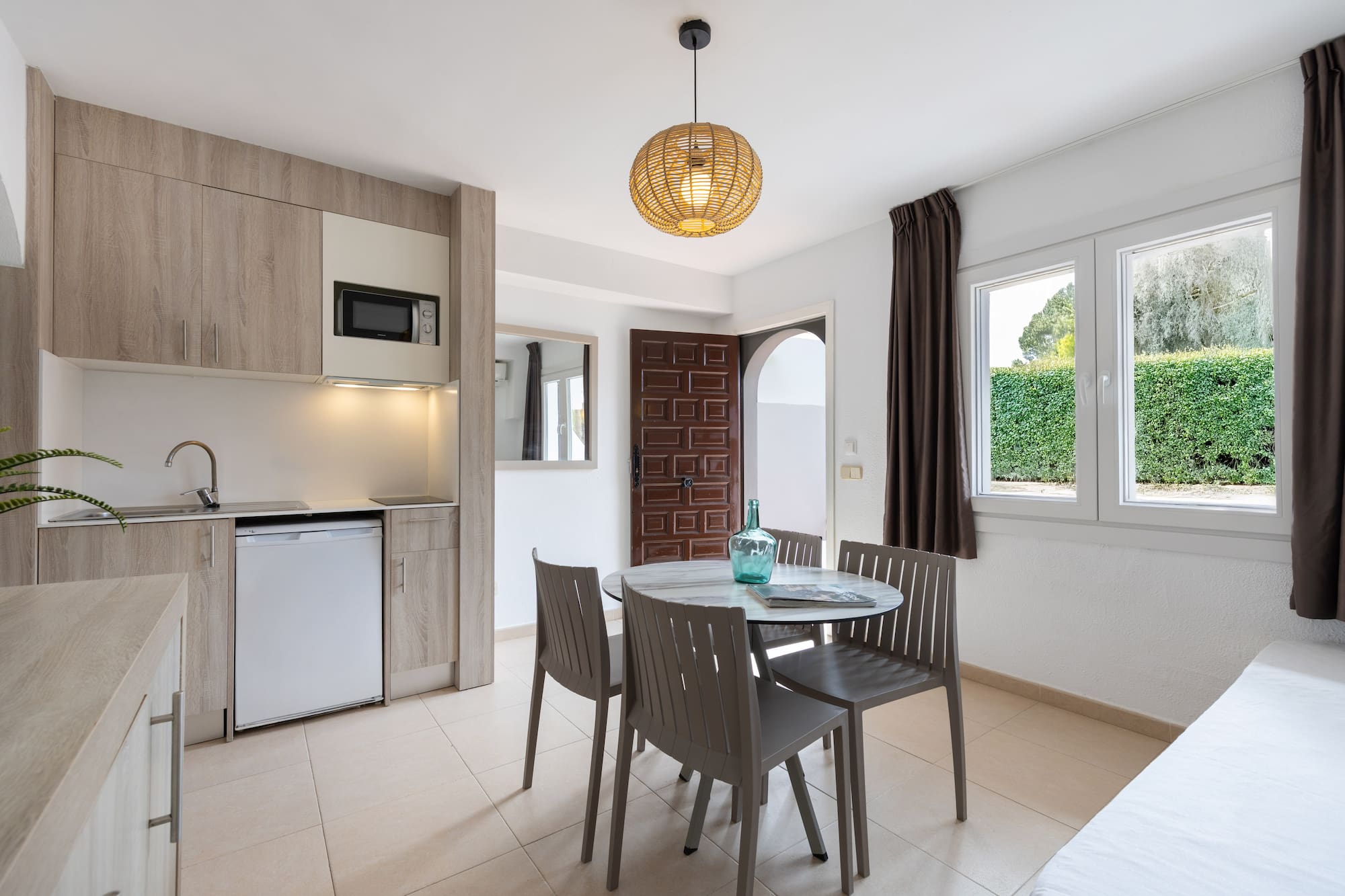 Modern studio apartment with kitchenette, dining table, and window.