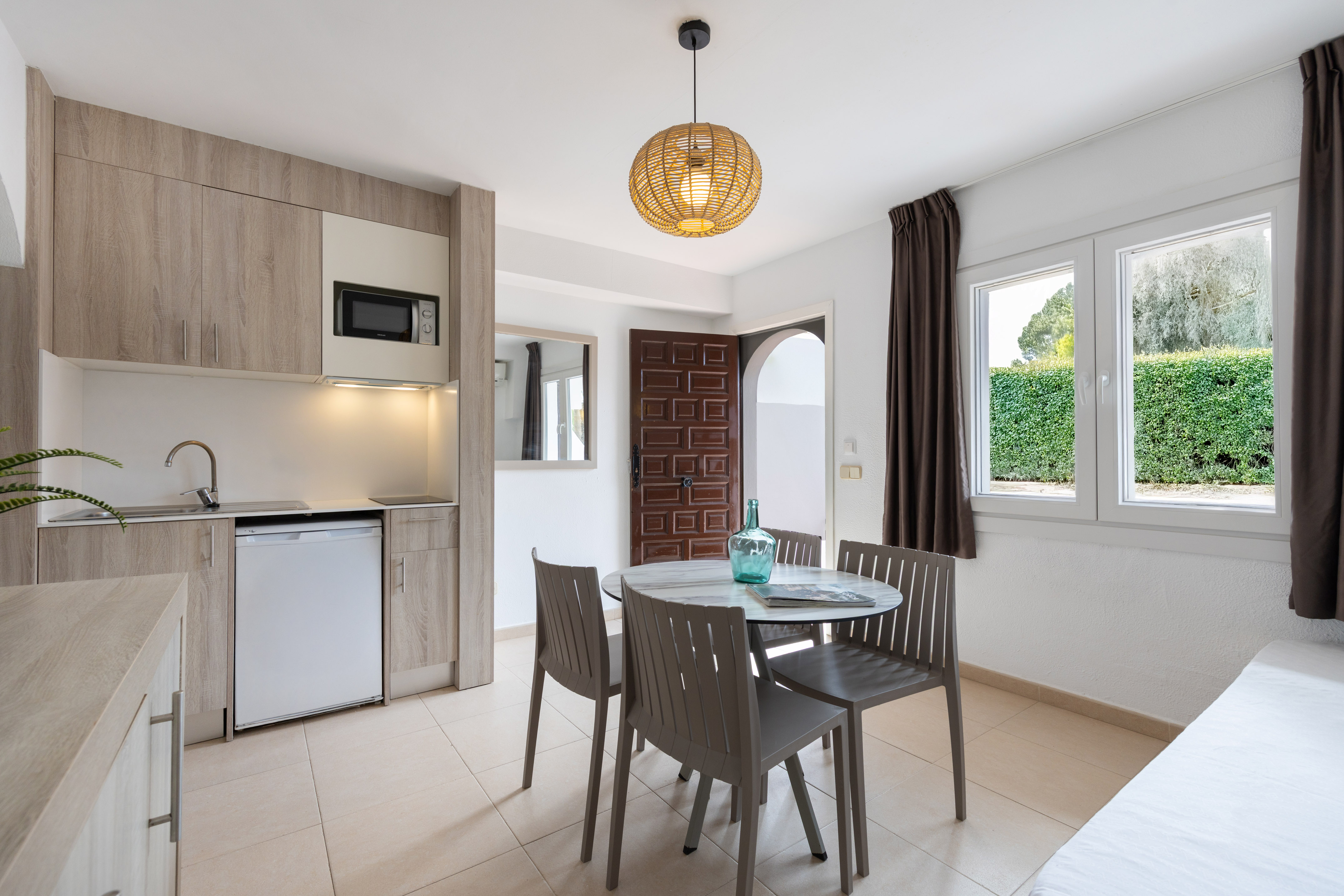 Modern studio apartment with kitchenette, dining table, and window.