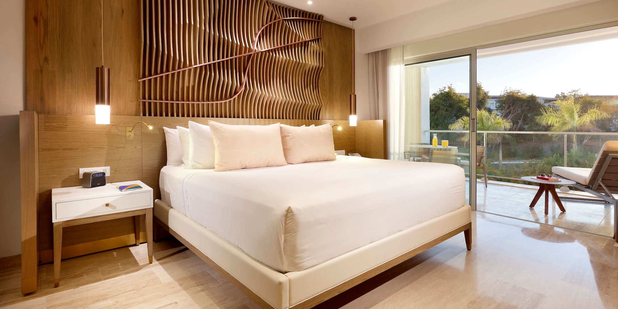Modern hotel bedroom with king bed, wood accent wall, and balcony.
