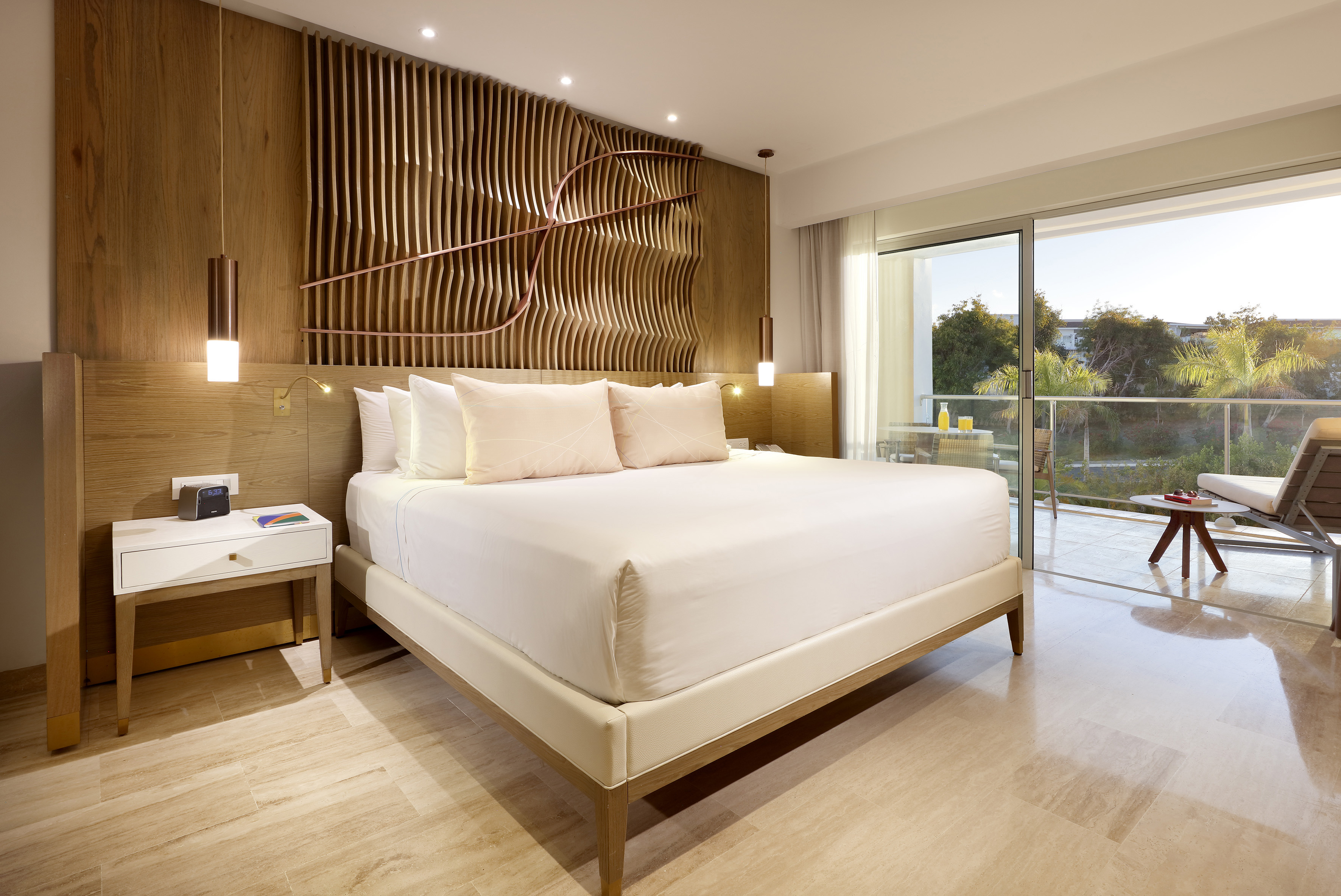 Modern hotel bedroom with king bed, wood accent wall, and balcony.