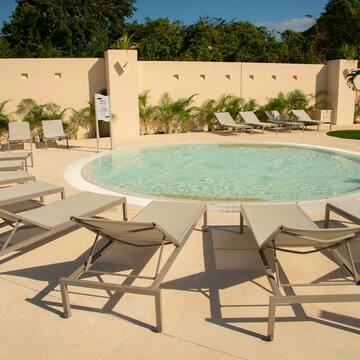 a pool with lounge chairs and a wall