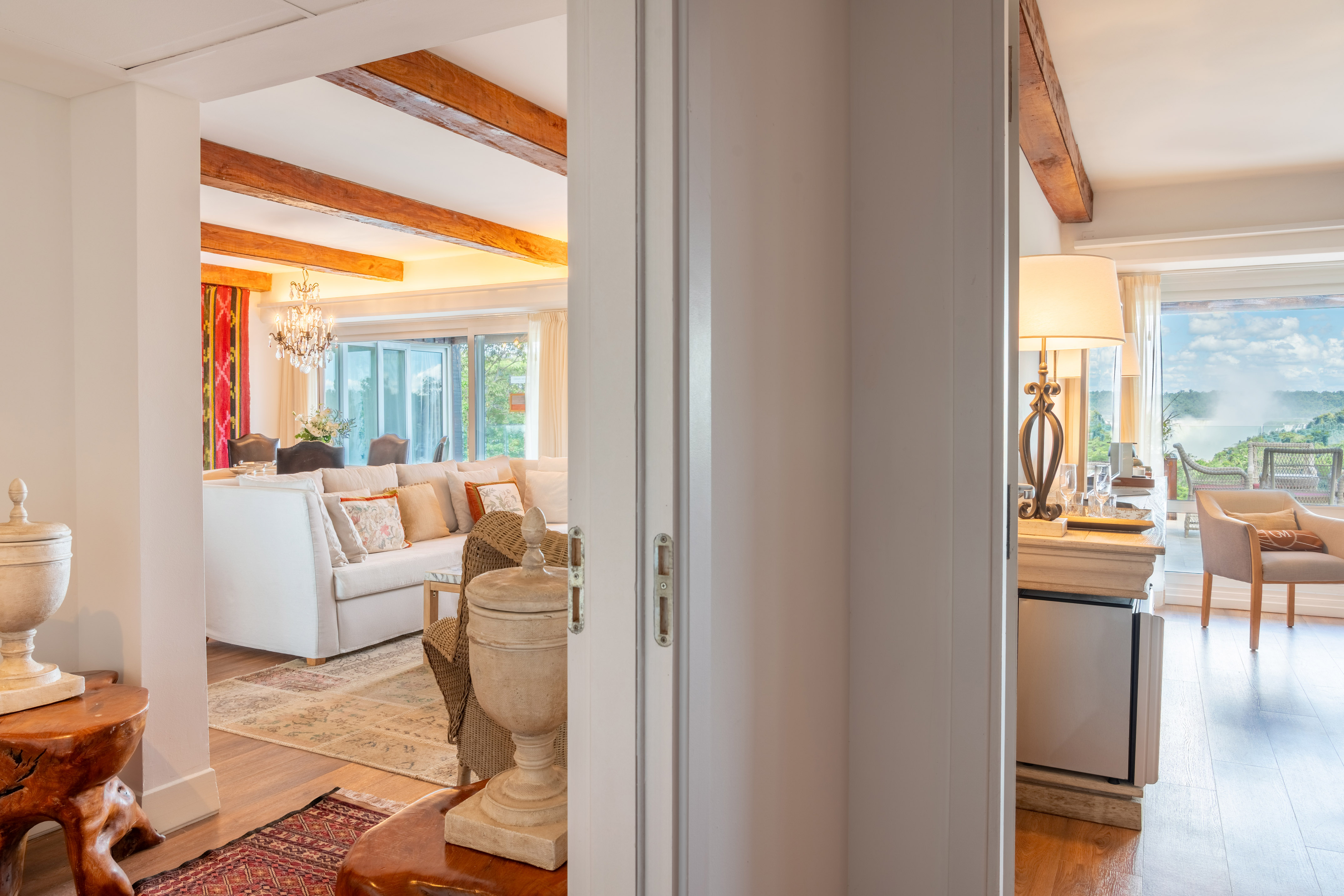 Open concept living room with exposed beams and panoramic waterfall view.