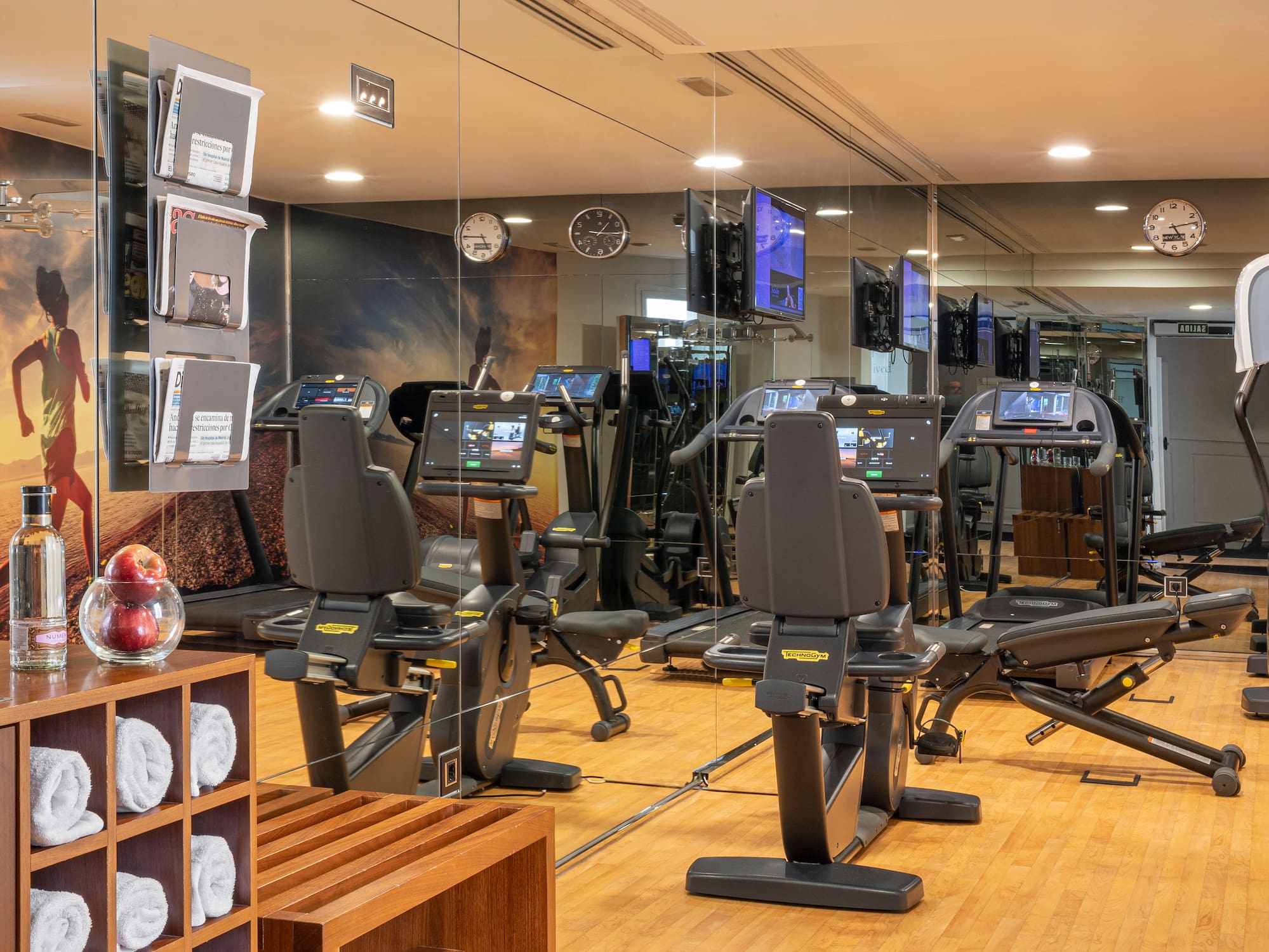 Modern gym with Technogym treadmills, recumbent bikes, and mirrored walls.