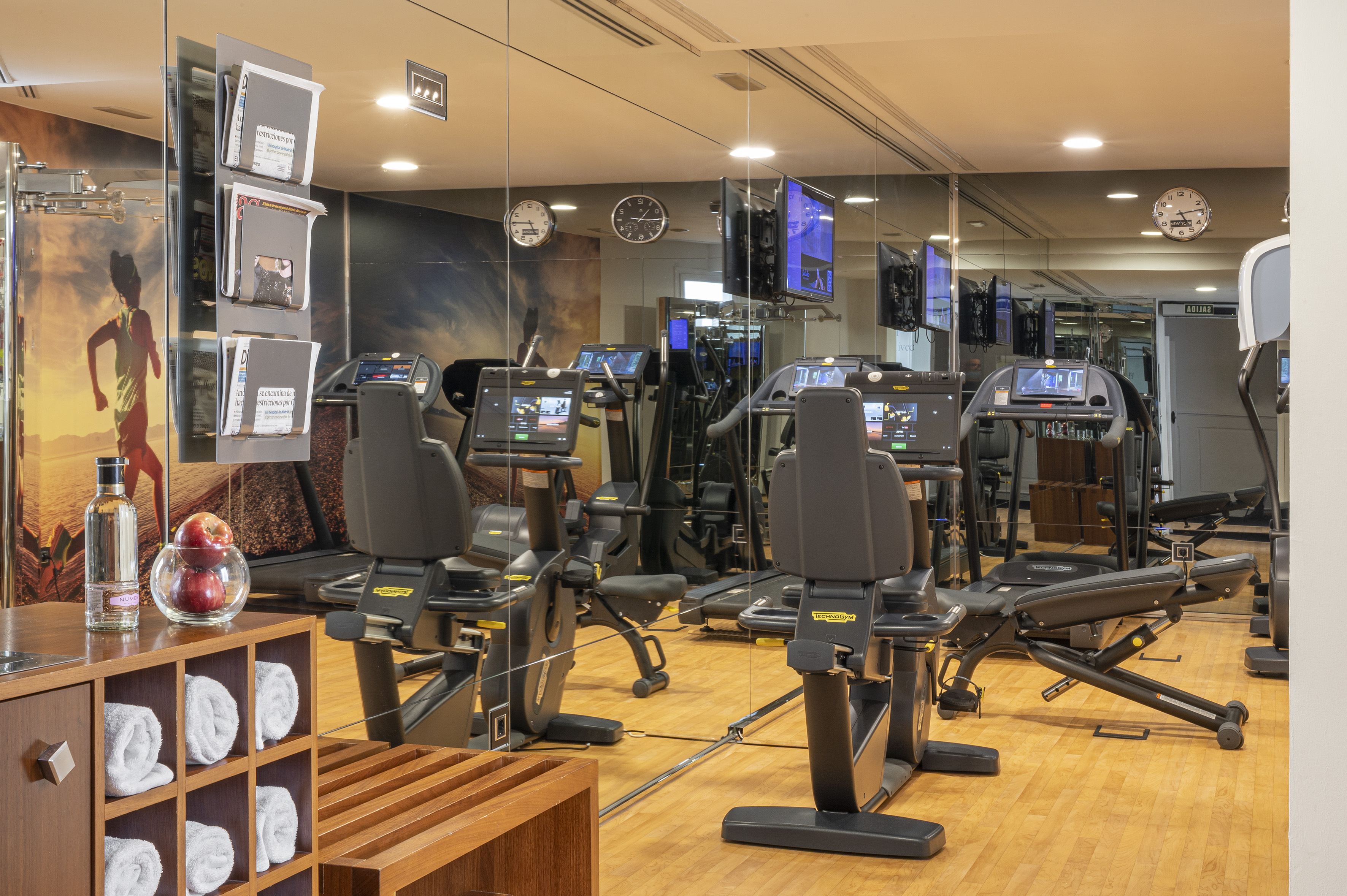 Modern gym with Technogym treadmills, recumbent bikes, and mirrored walls.