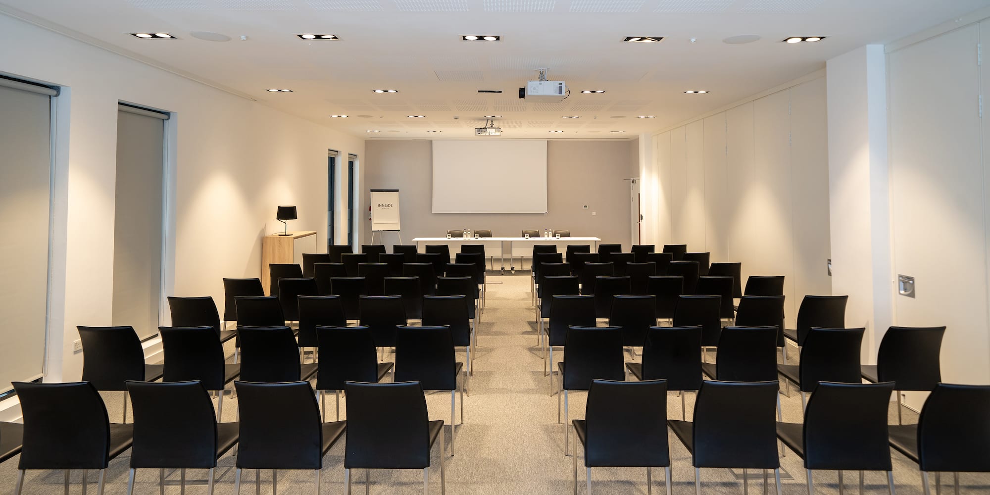 a room with black chairs and a projector screen