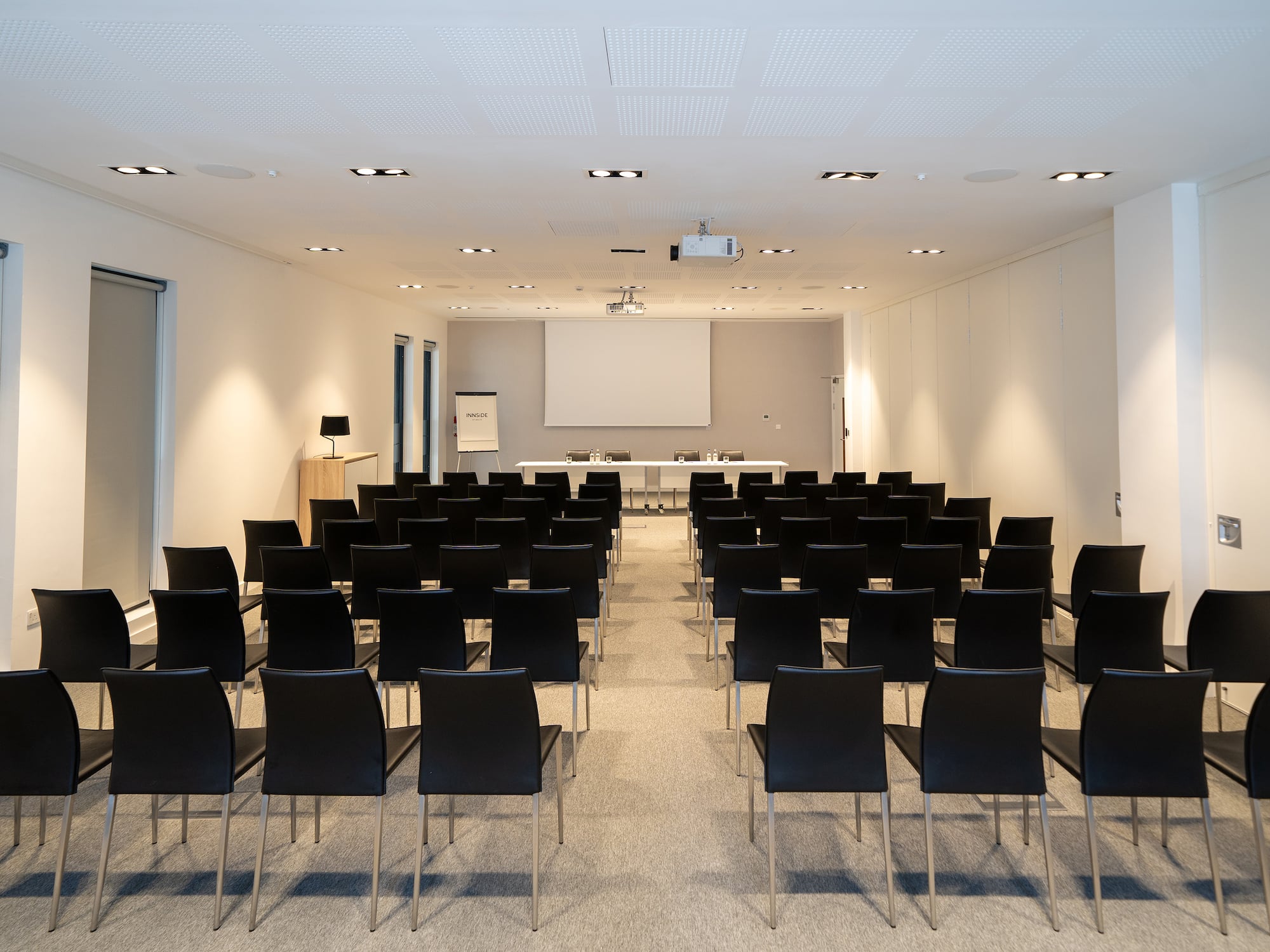 a room with black chairs and a projector screen