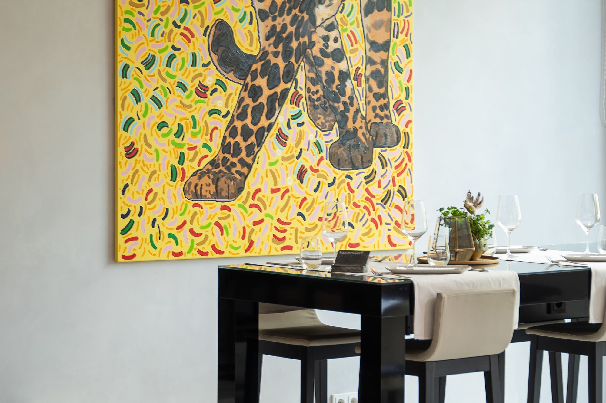 Modern dining room with vibrant leopard painting and set bar table.