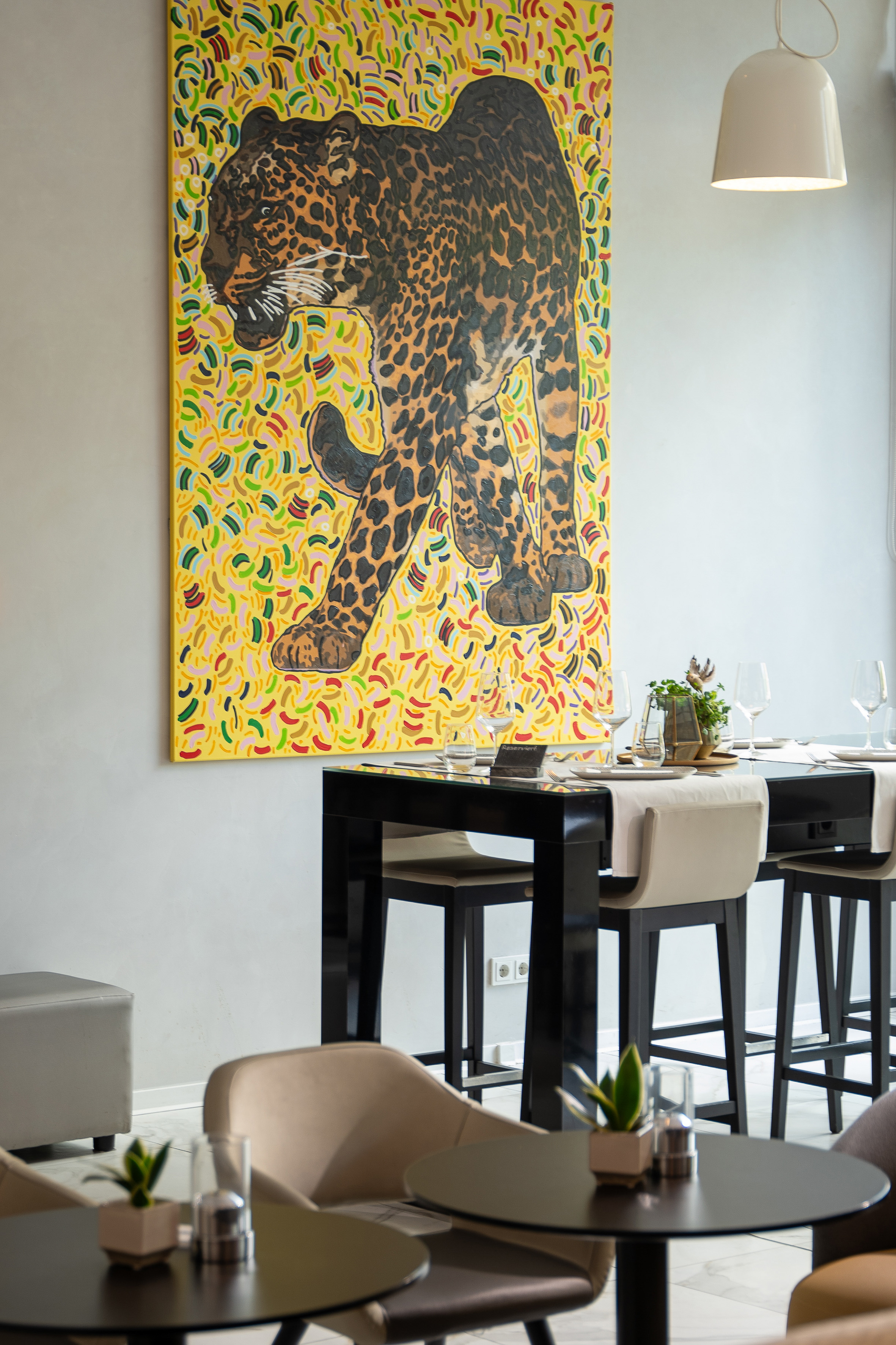 Modern dining room with vibrant leopard painting and set bar table.