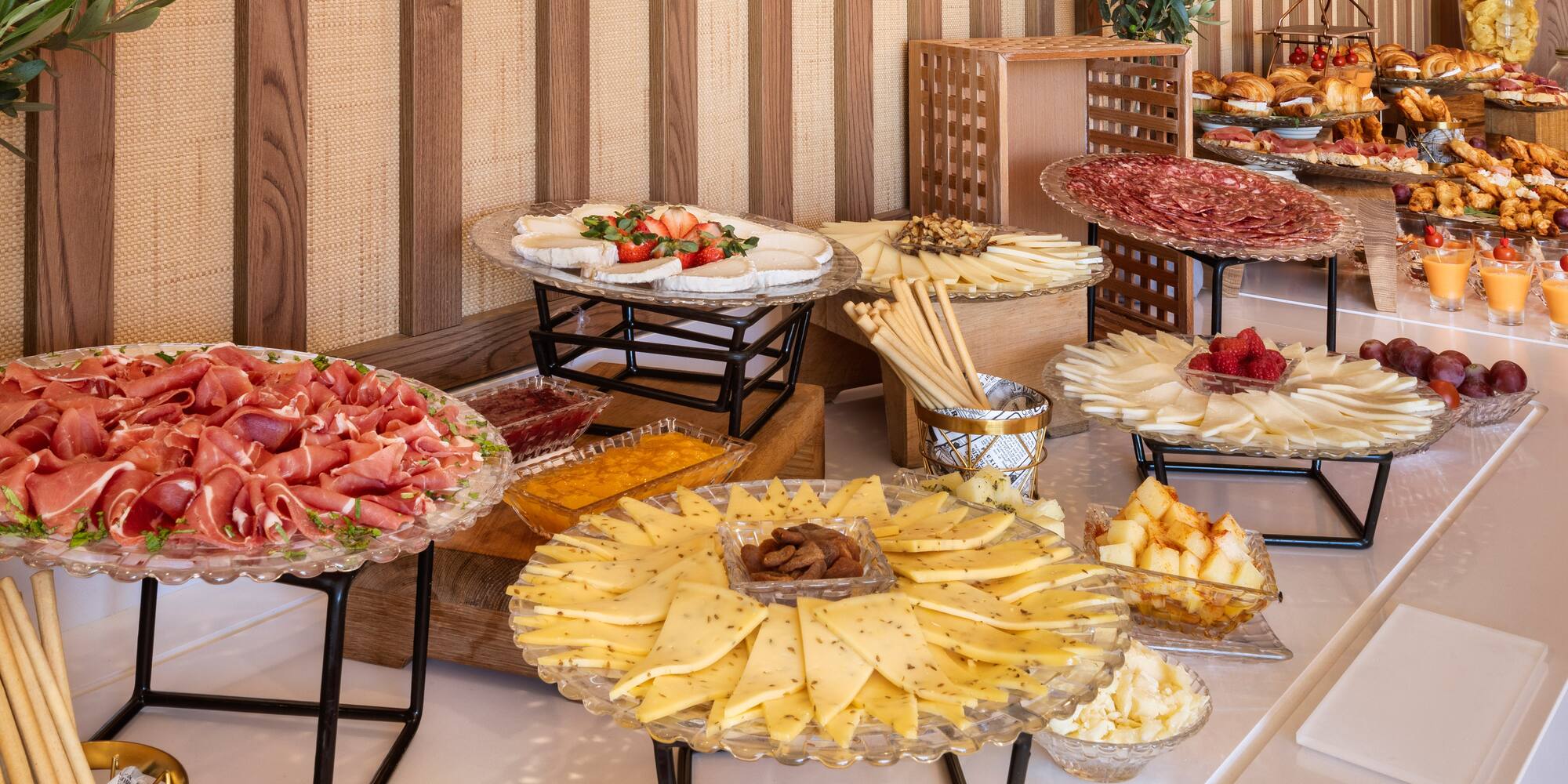 Hotel breakfast buffet with charcuterie, assorted cheeses, pastries, and fruit.