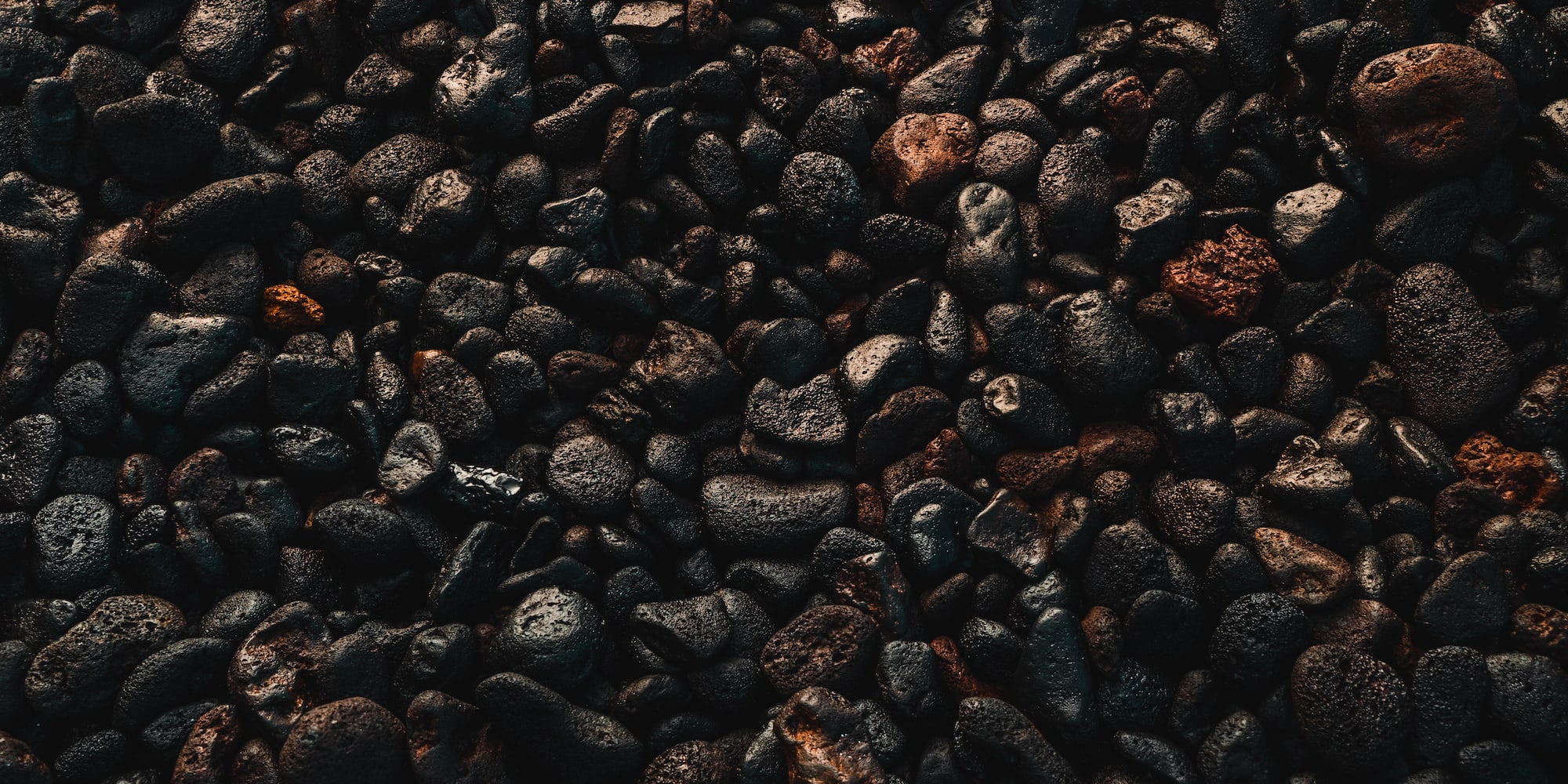 Detalle de piedras volcánicas oscuras, texturas ásperas y tonos rojizos.