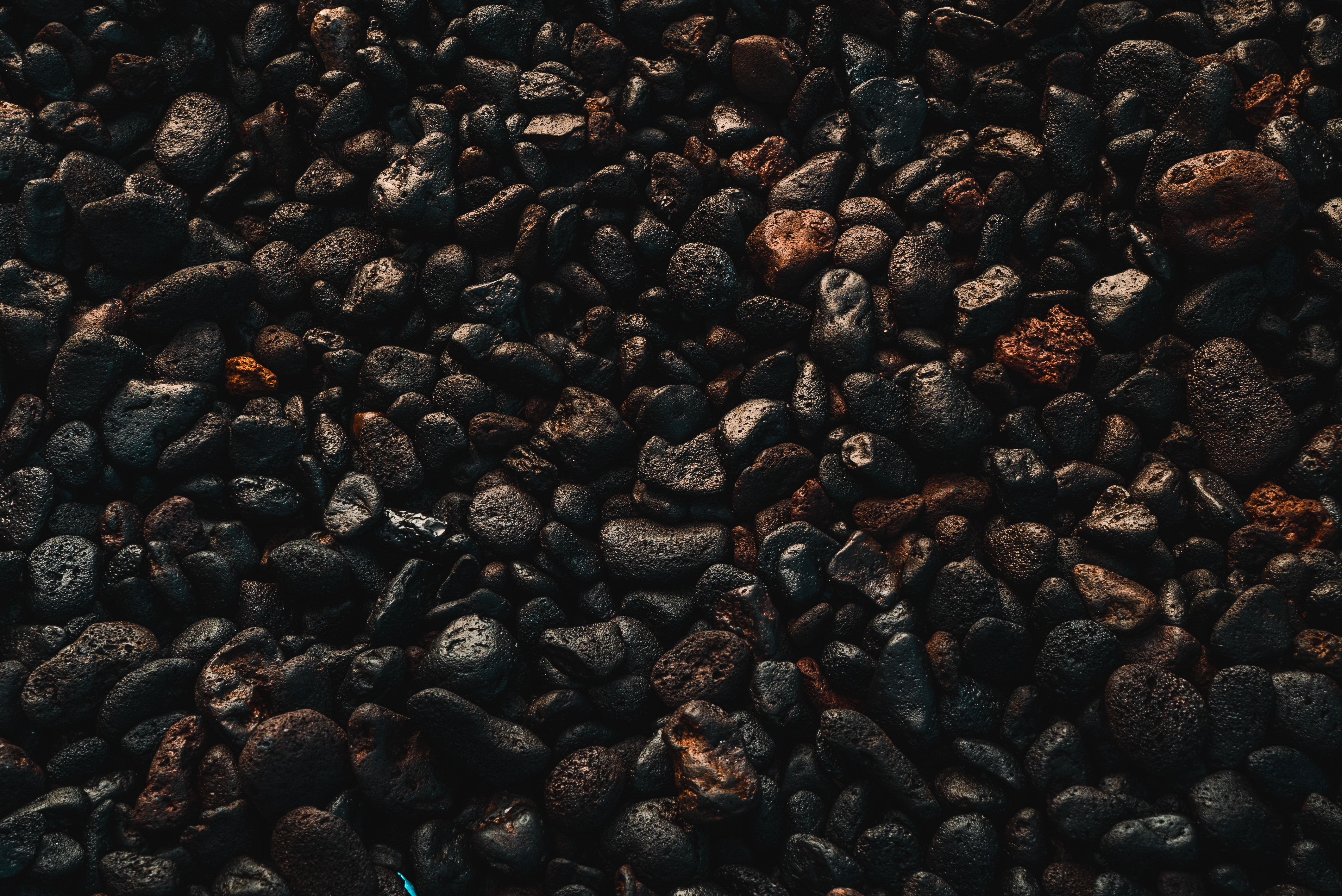 Detalle de piedras volcánicas oscuras, texturas ásperas y tonos rojizos.