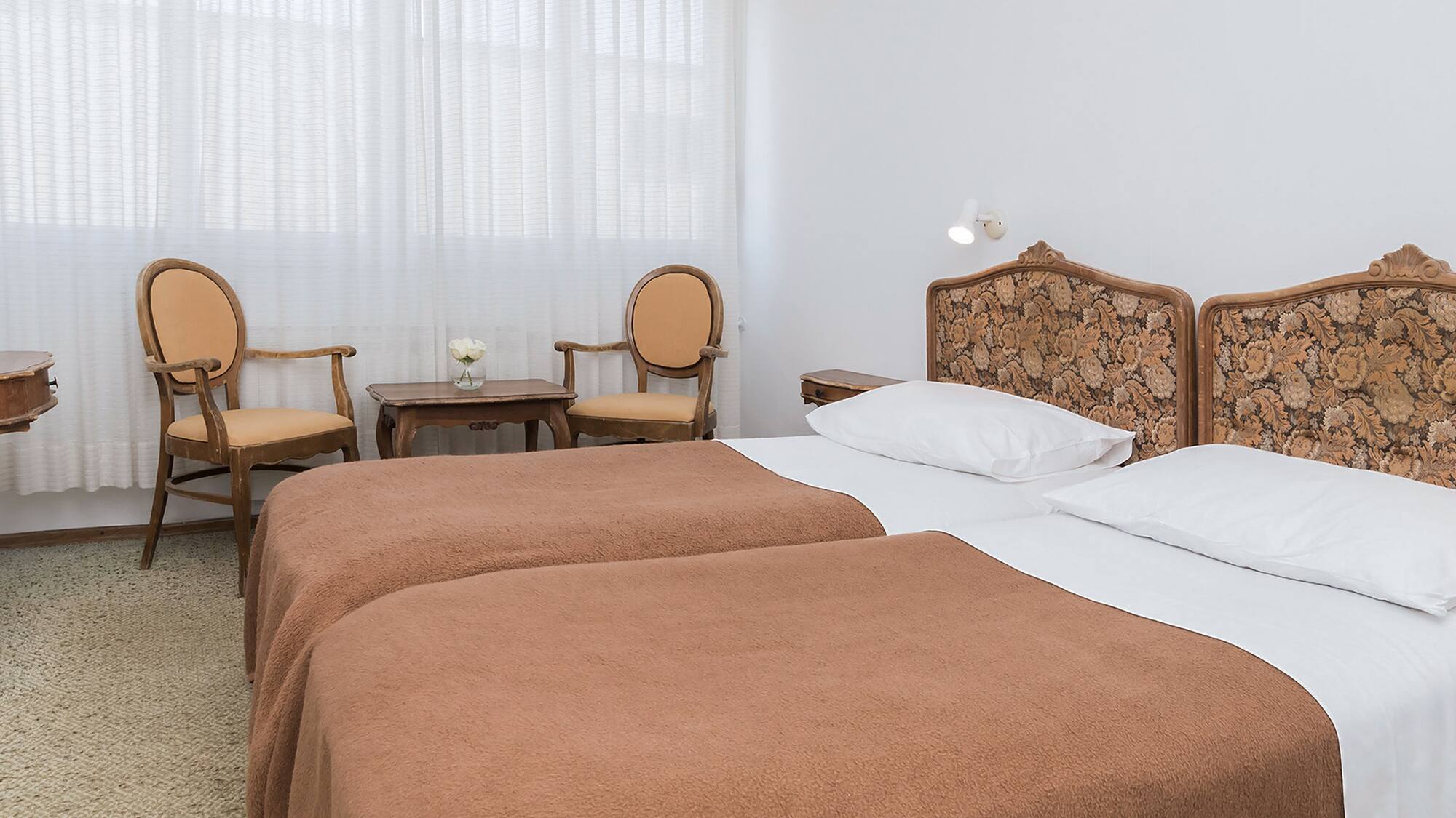 a room with two beds and chairs