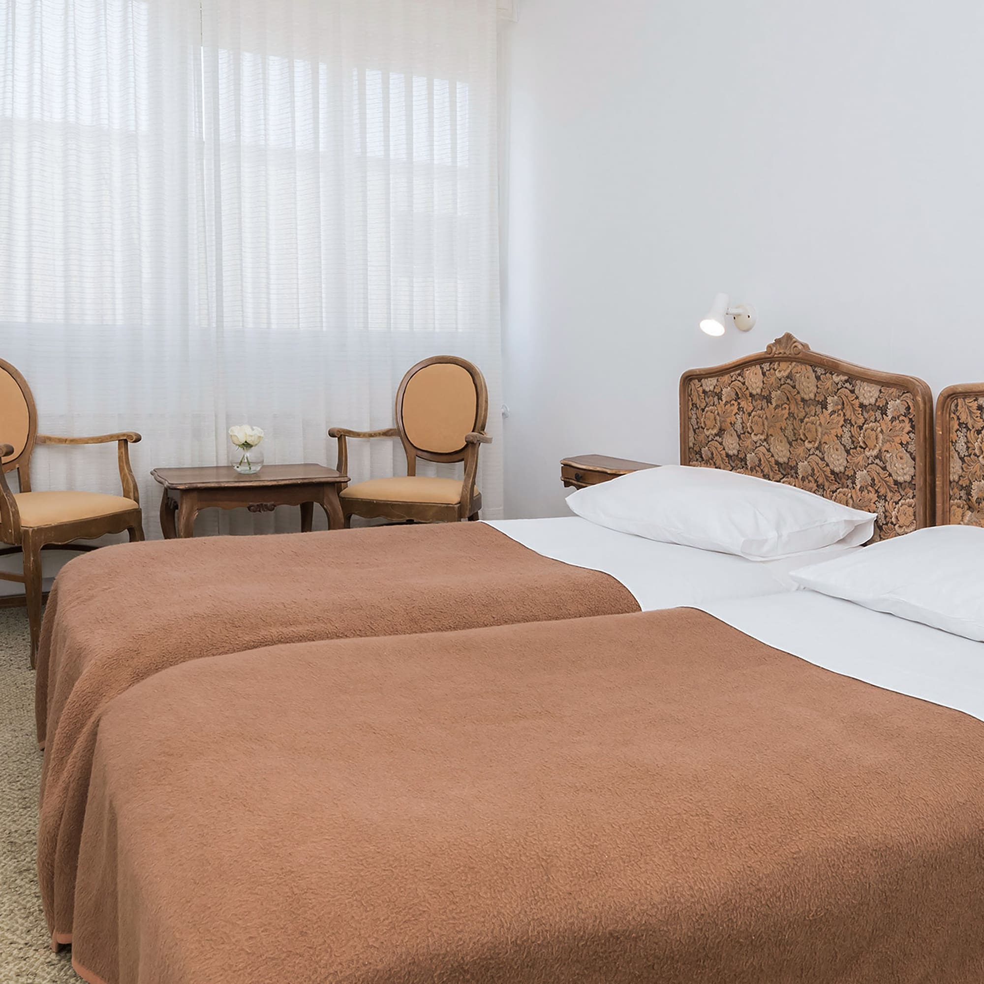 a room with two beds and chairs