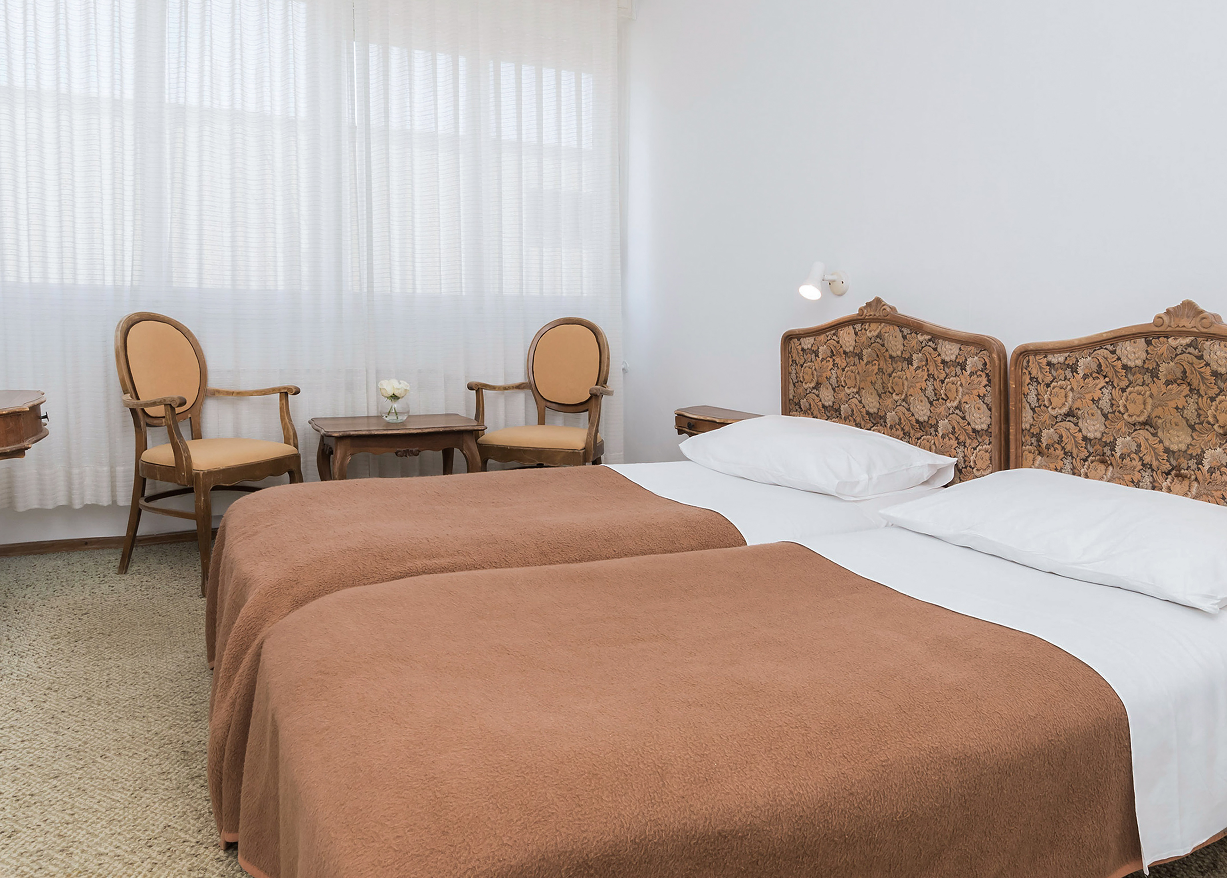 a room with two beds and chairs