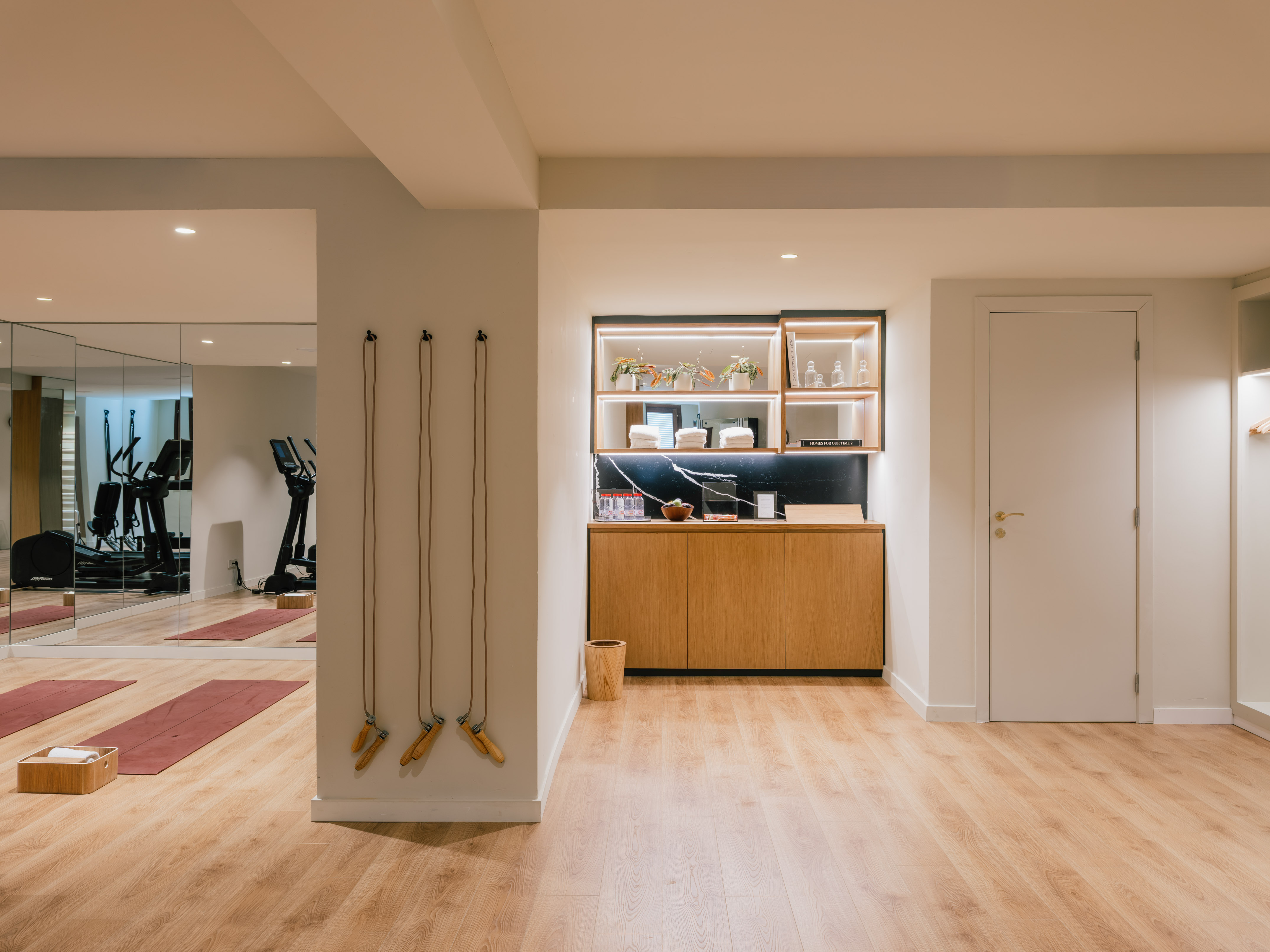 Modern fitness studio with yoga mats, jump ropes, and reflected gym equipment.