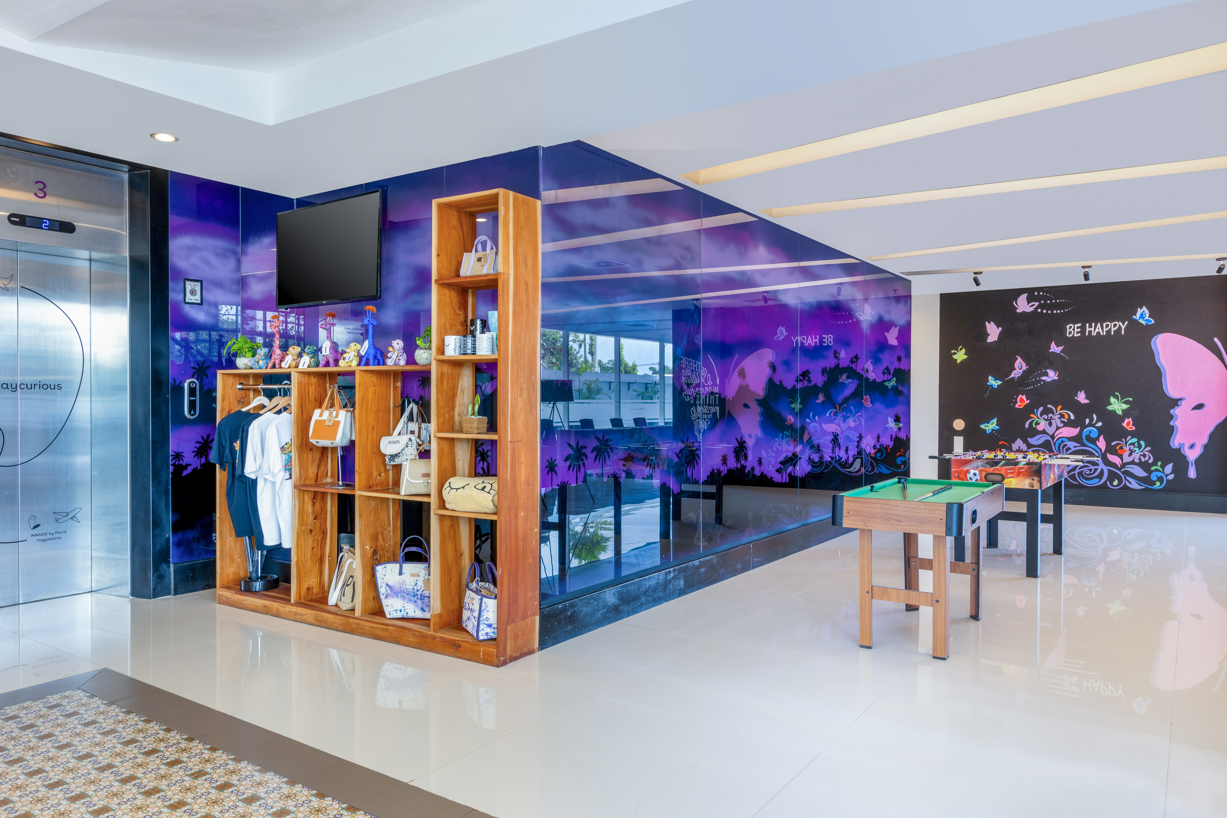 Innside by Melia modern hotel lounge with purple decor, games, and merchandise display.