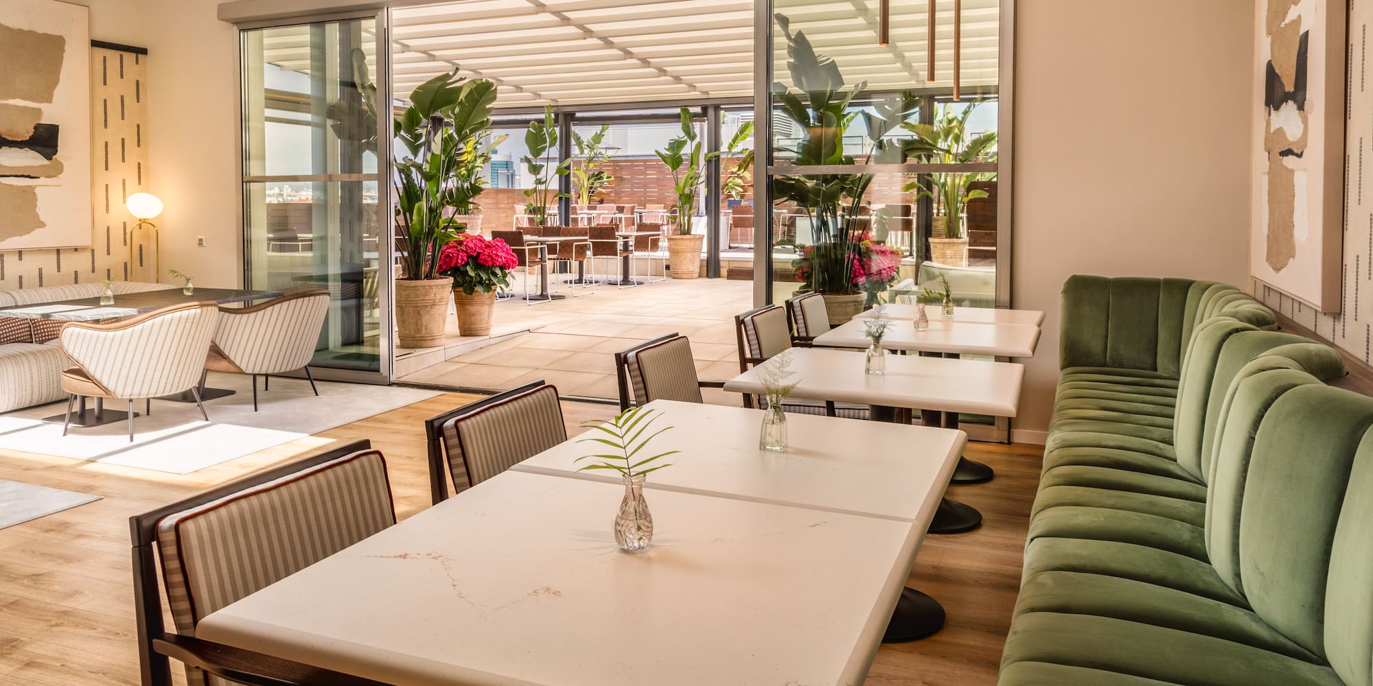 Modern restaurant dining area with green banquette and outdoor terrace.