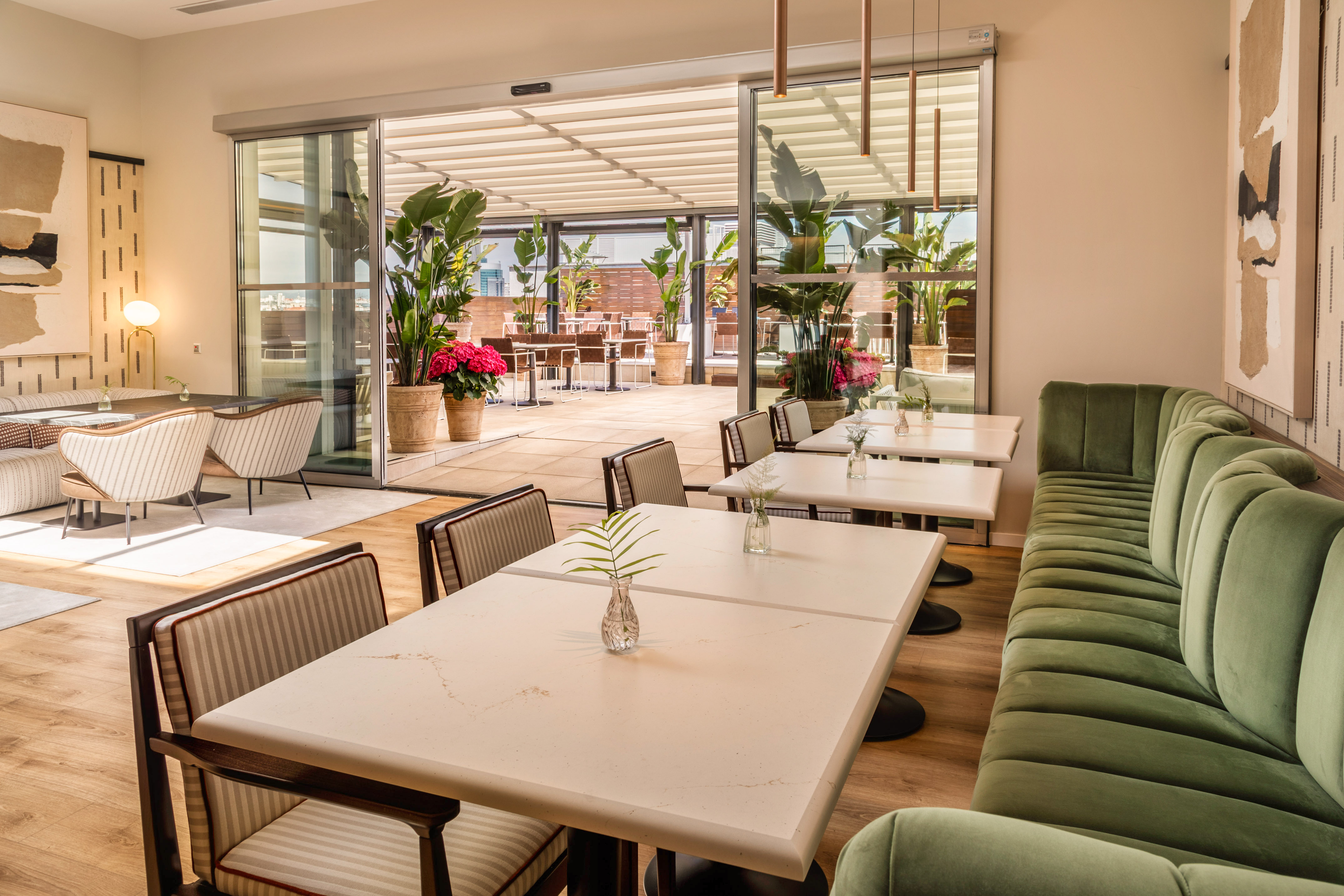 Modern restaurant dining area with green banquette and outdoor terrace.