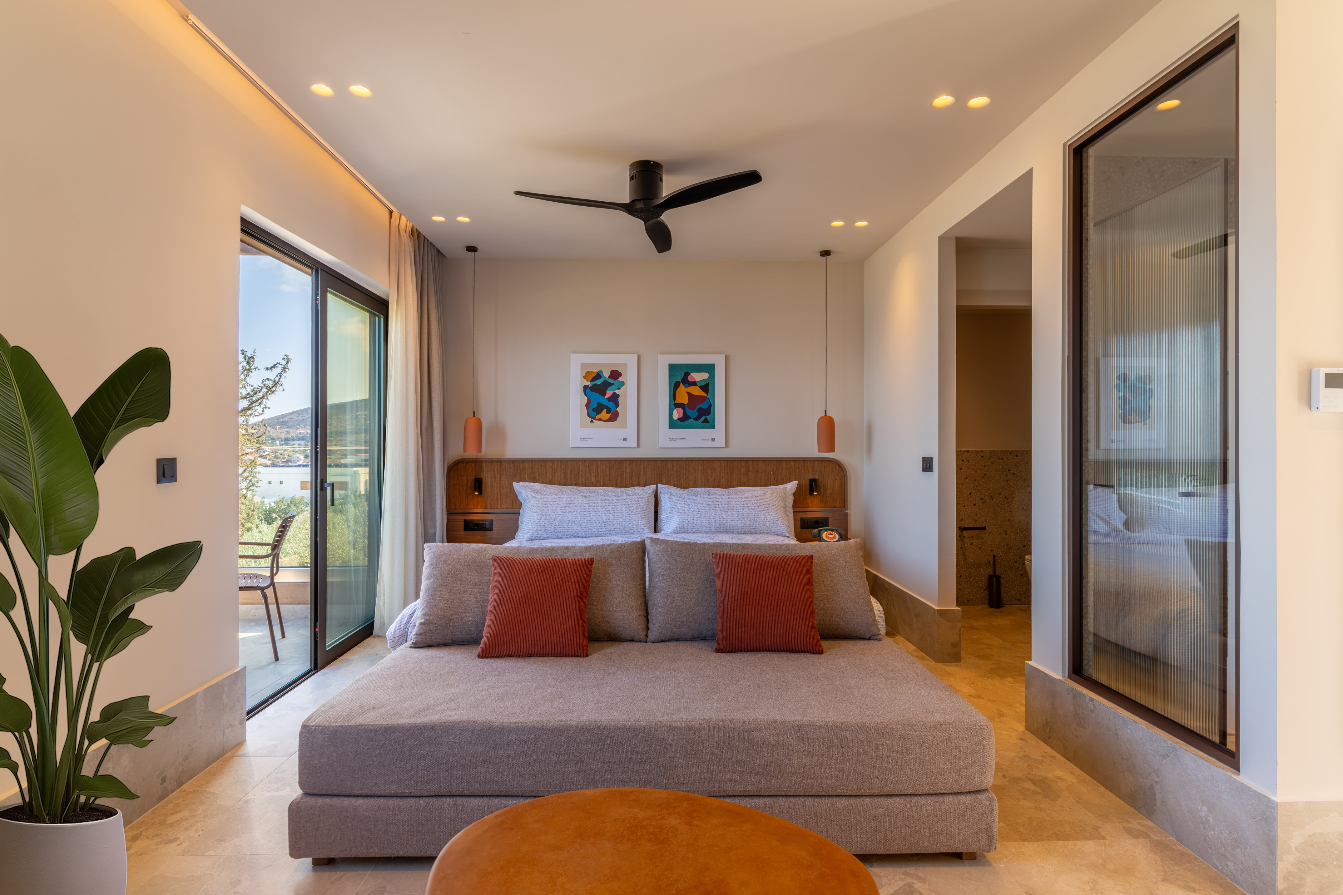 Modern hotel bedroom with daybed, abstract art, and balcony sea view.